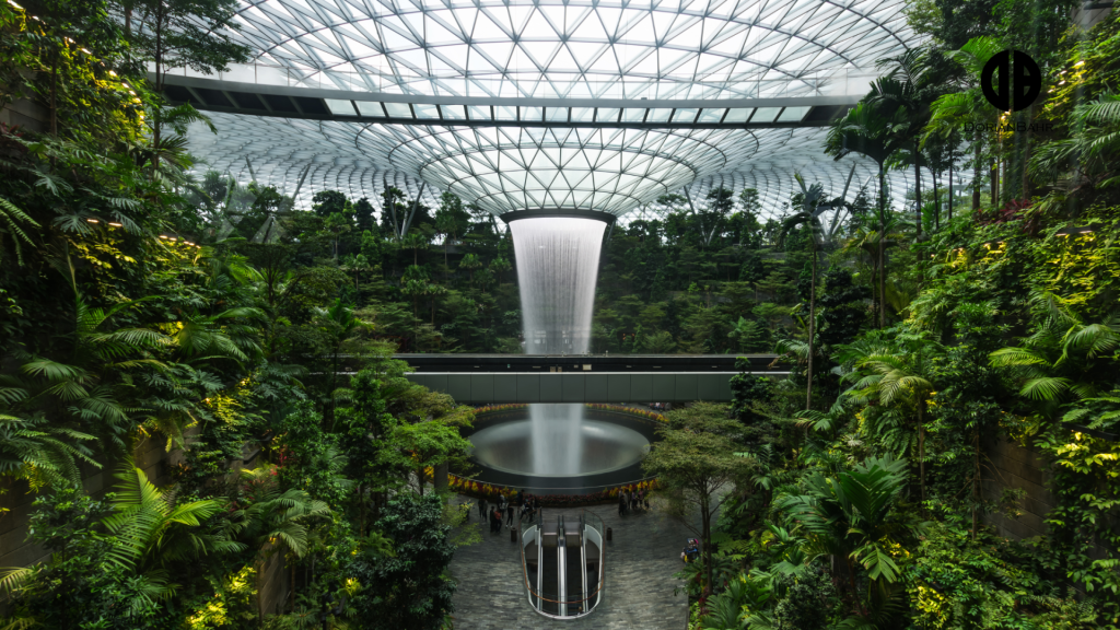 A large building with a waterfall in the middle of it surrounded by trees.
