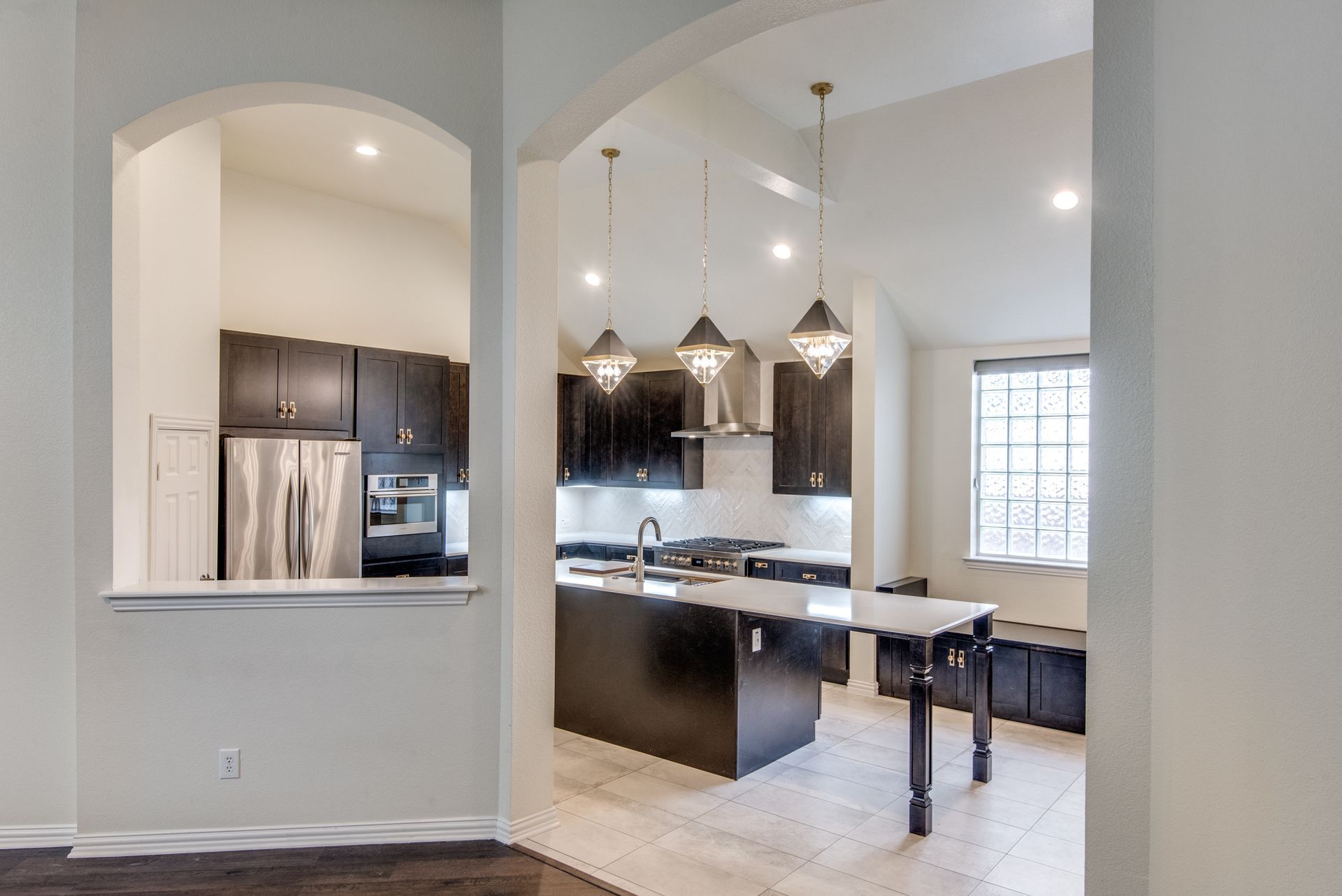 A kitchen with black cabinets , stainless steel appliances , and a large island.