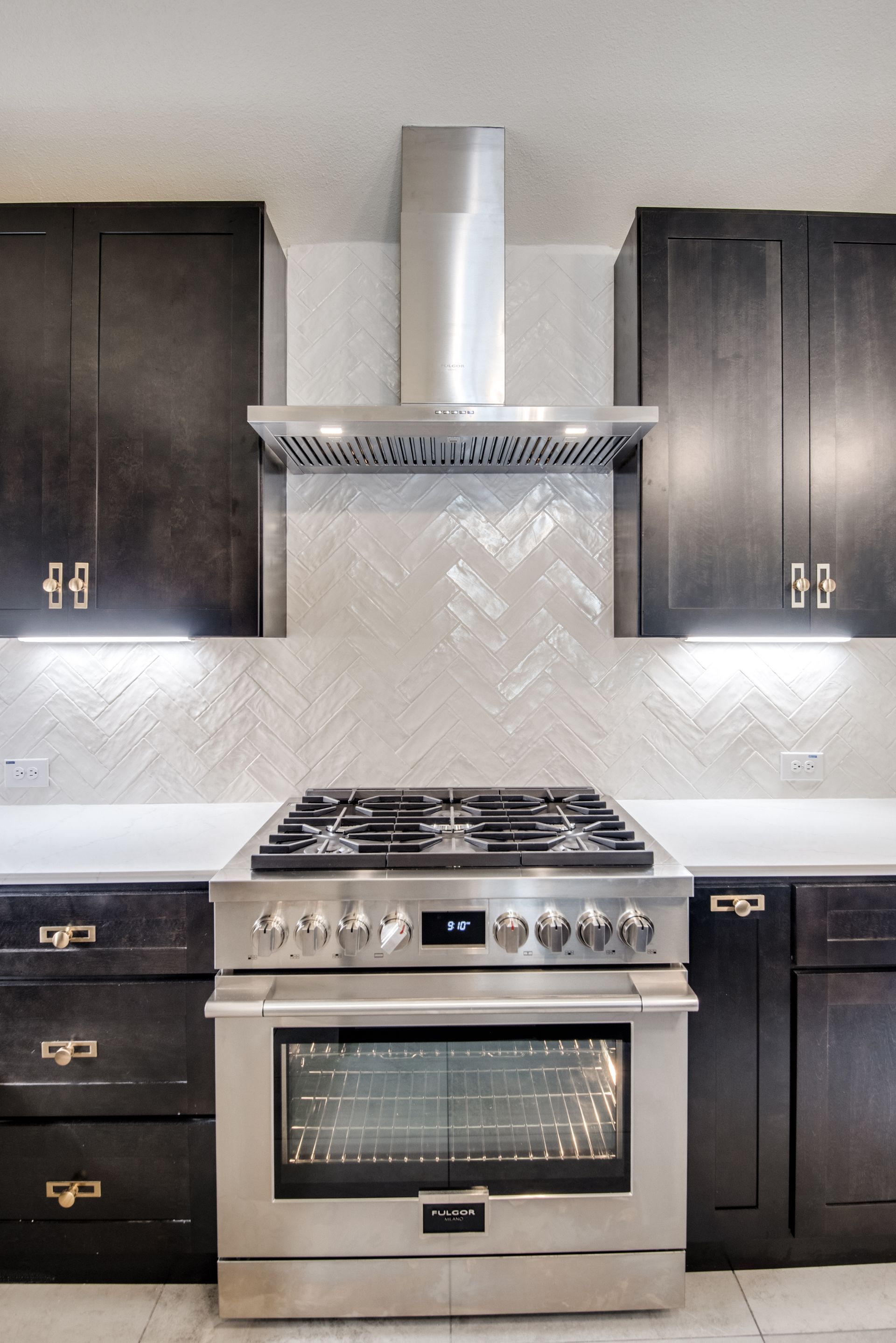 A kitchen with stainless steel appliances and black cabinets.