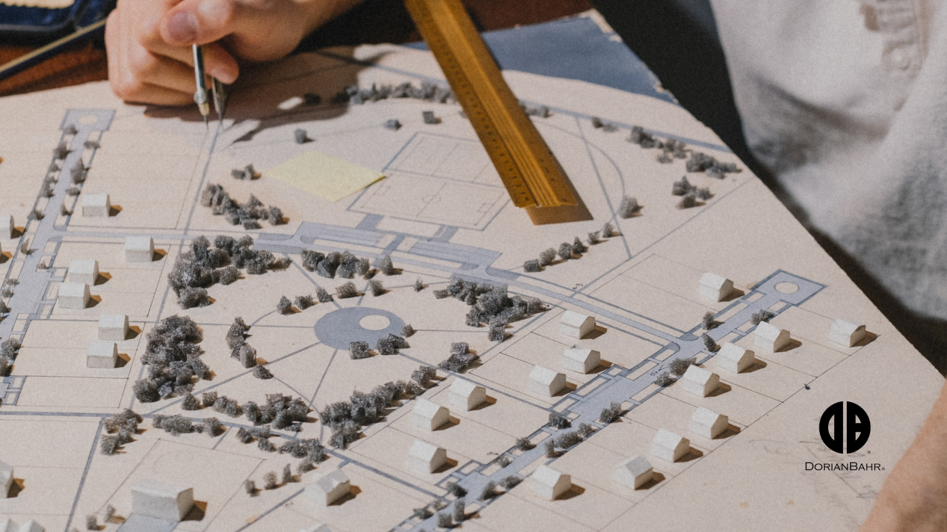 A person is measuring a model of a city with a ruler.