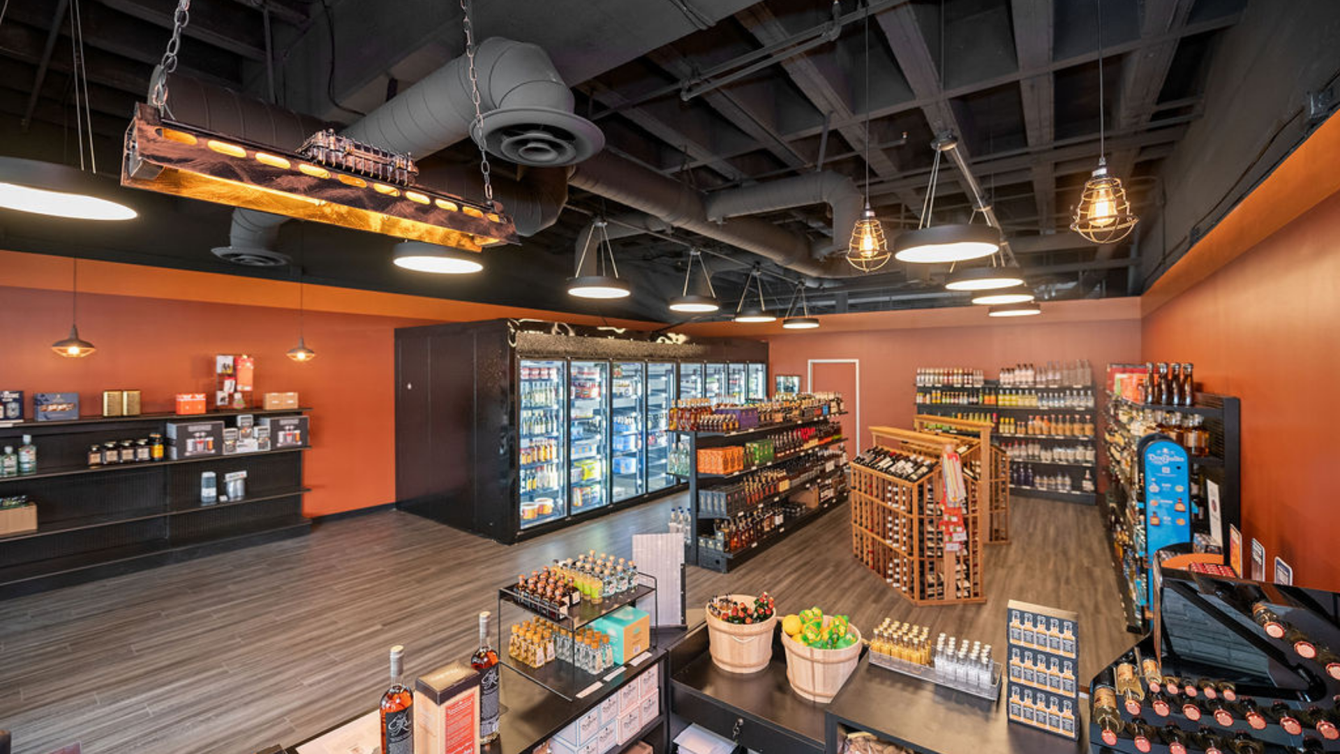 Grocery store interior with orange walls, black shelving, and various food and drink items.