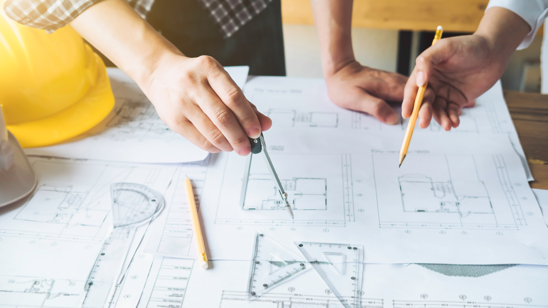 A couple of people are sitting at a table looking at a blueprint.