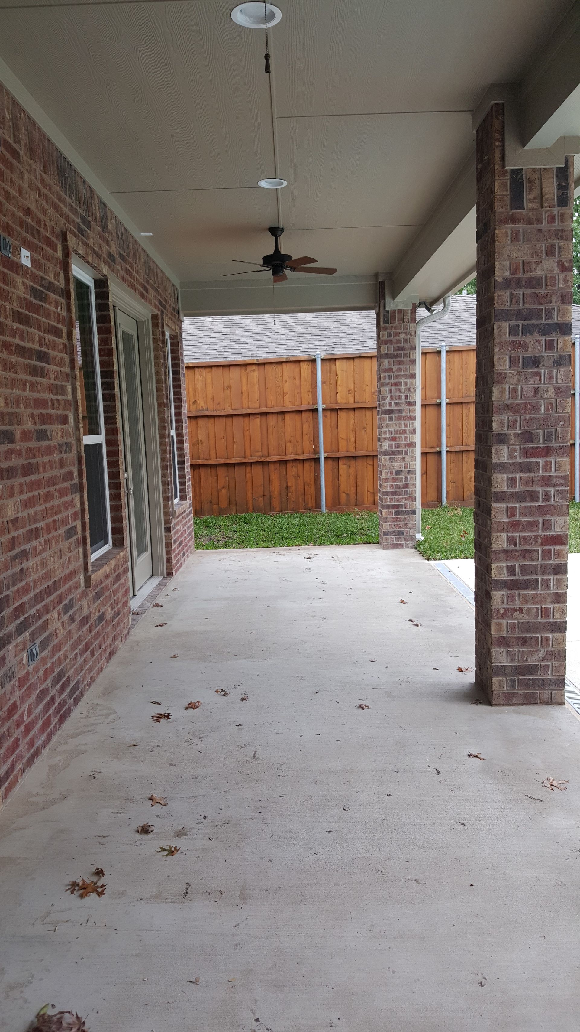 A patio remodel with a ceiling fan and a wooden fence in the background.