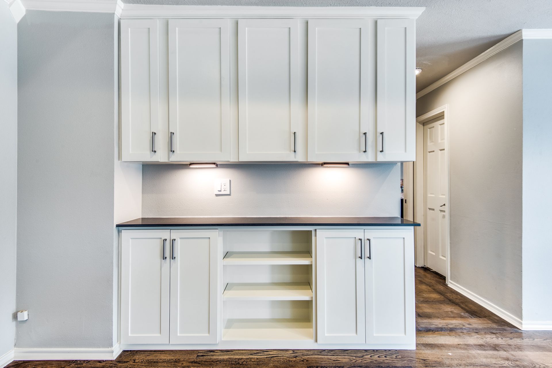 A Plano home remodel  kitchen with white cabinets and a black counter top