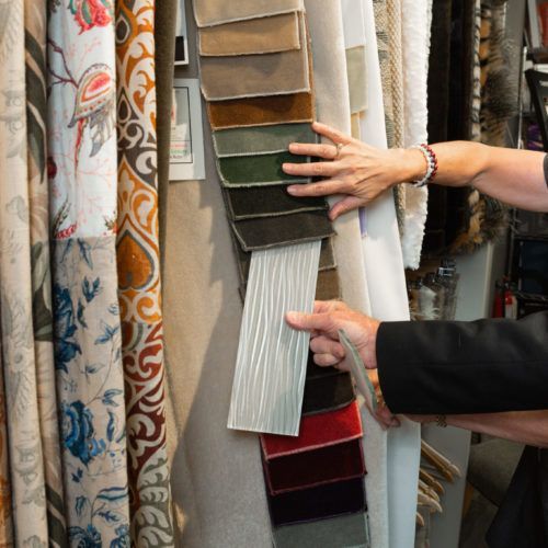 A man and woman are looking at fabric samples in a store