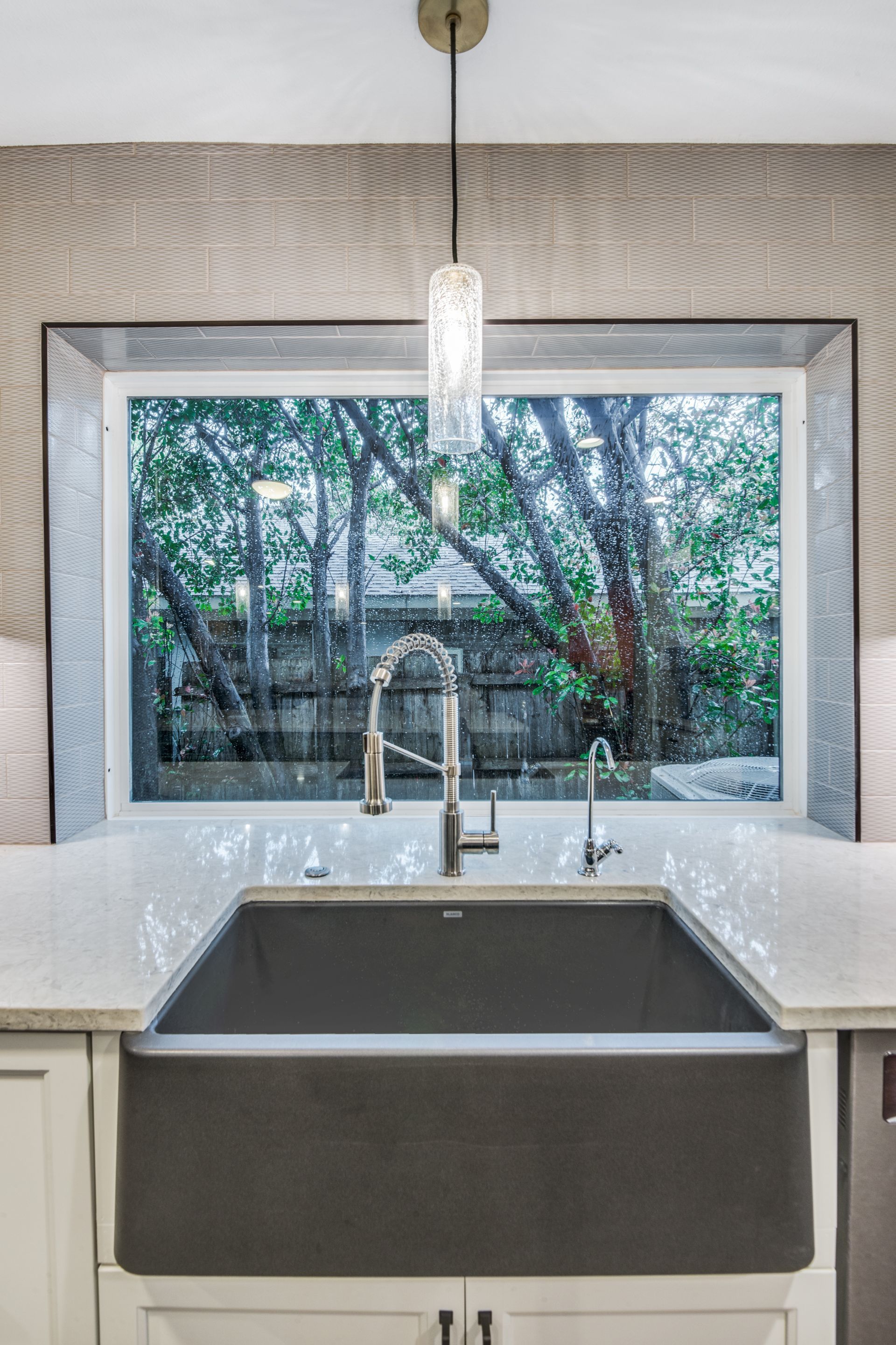 A kitchen with a sink and a window with trees in the background.
