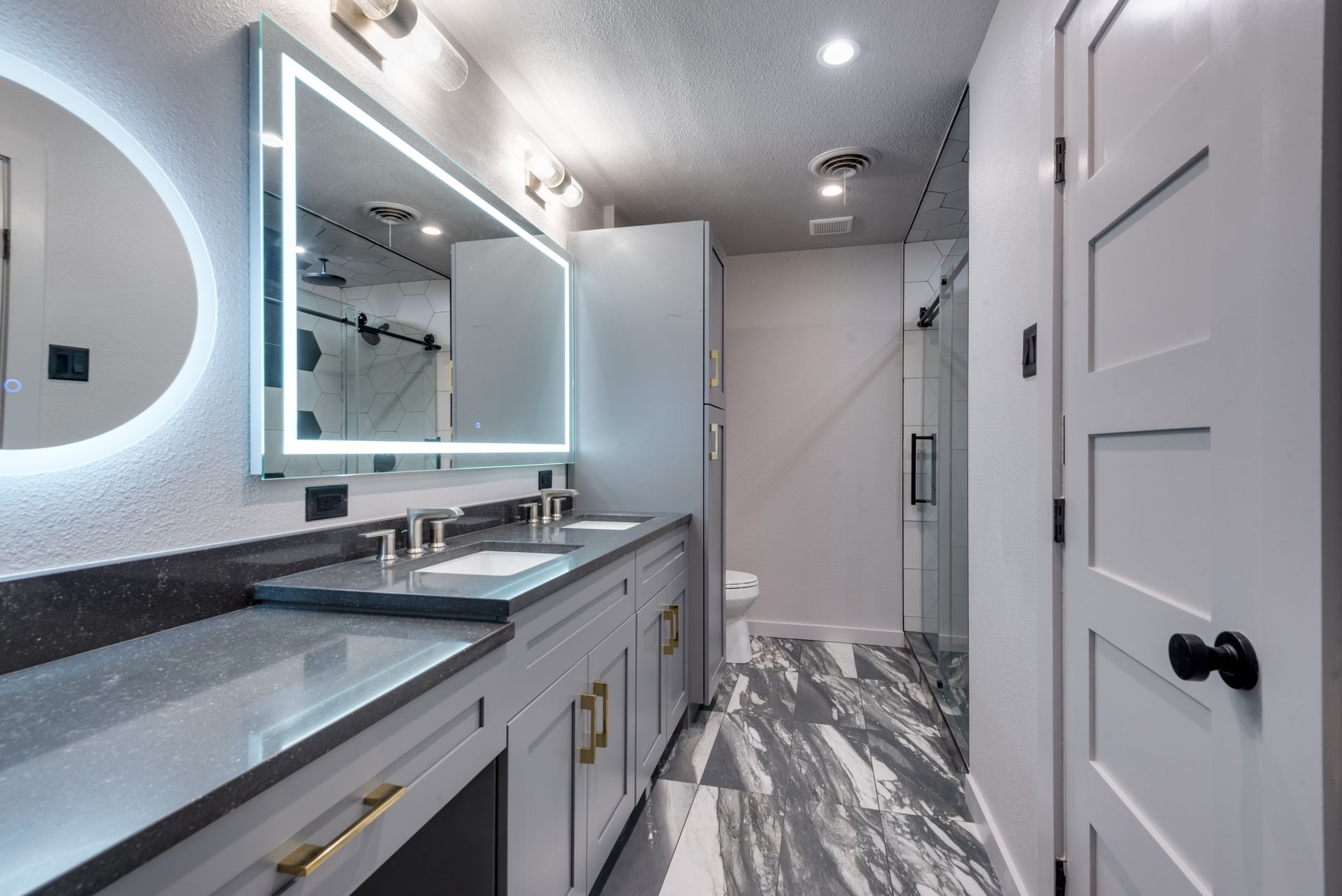 A bathroom remodel with two sinks , a mirror and a toilet.