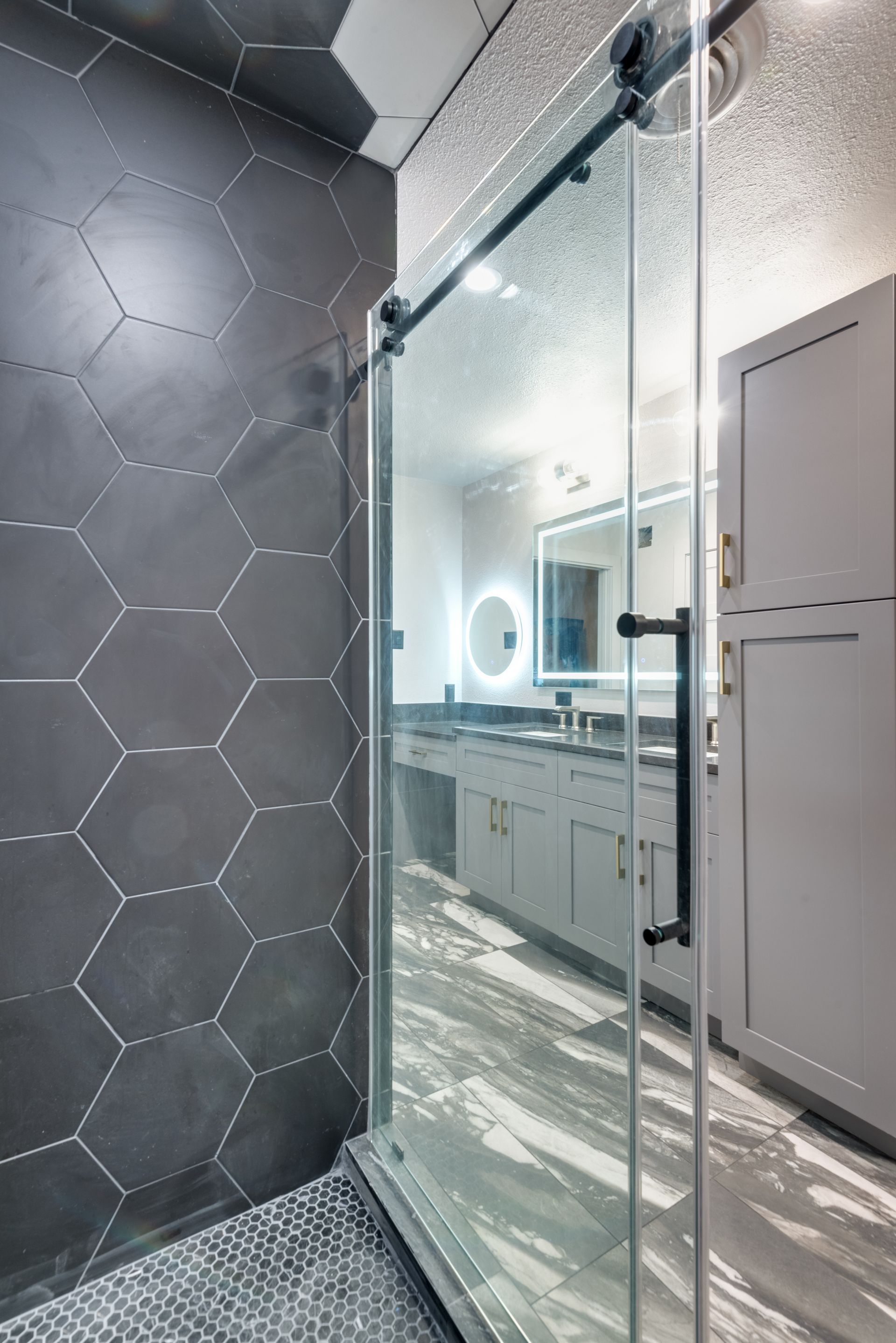A bathroom remodel with a sliding glass shower door and a mirror.