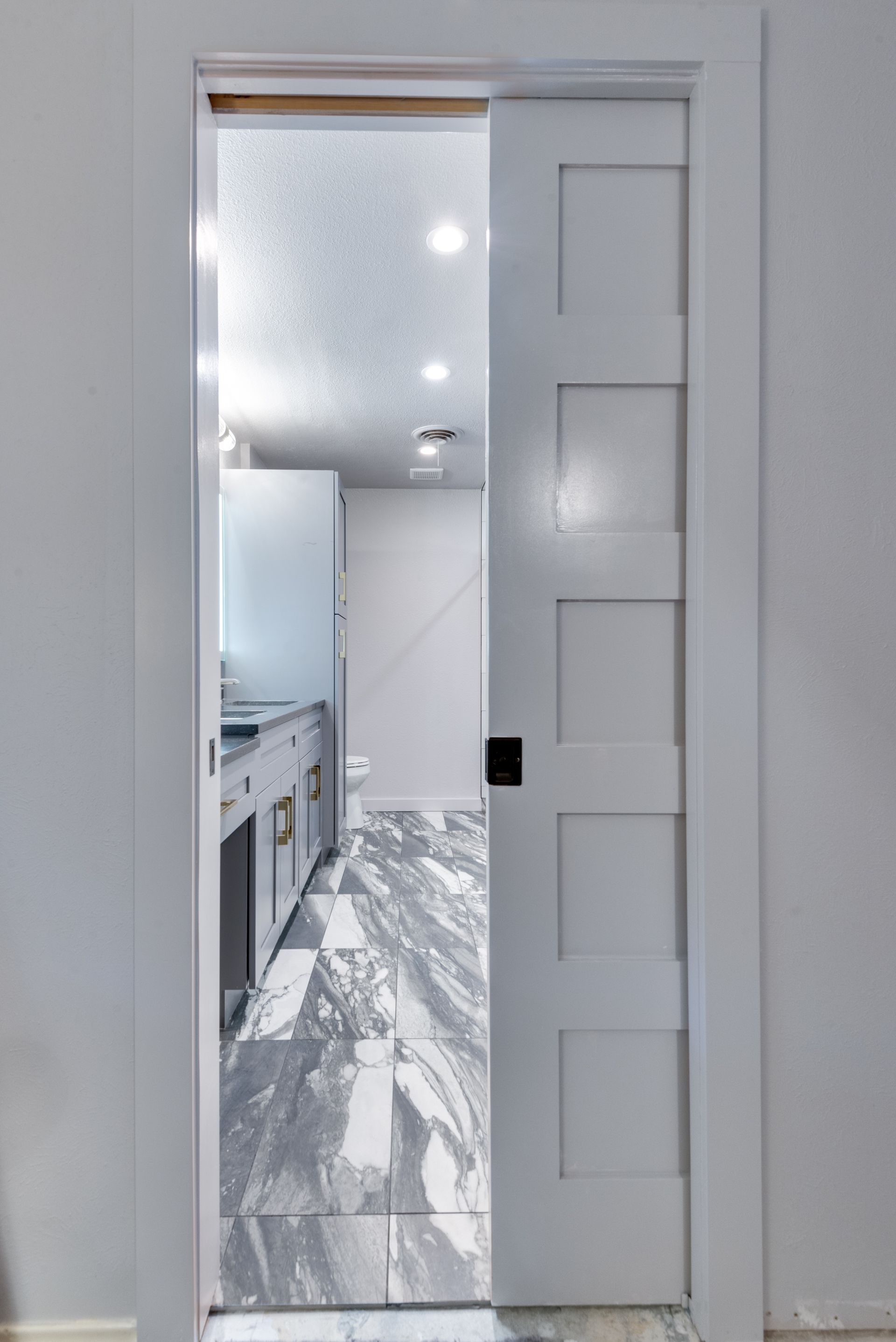 A white sliding door is open to a bathroom remodel.