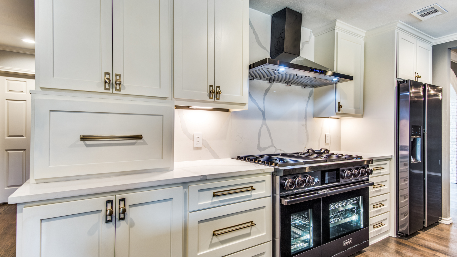White kitchen with a black stove, range hood, and refrigerator.
