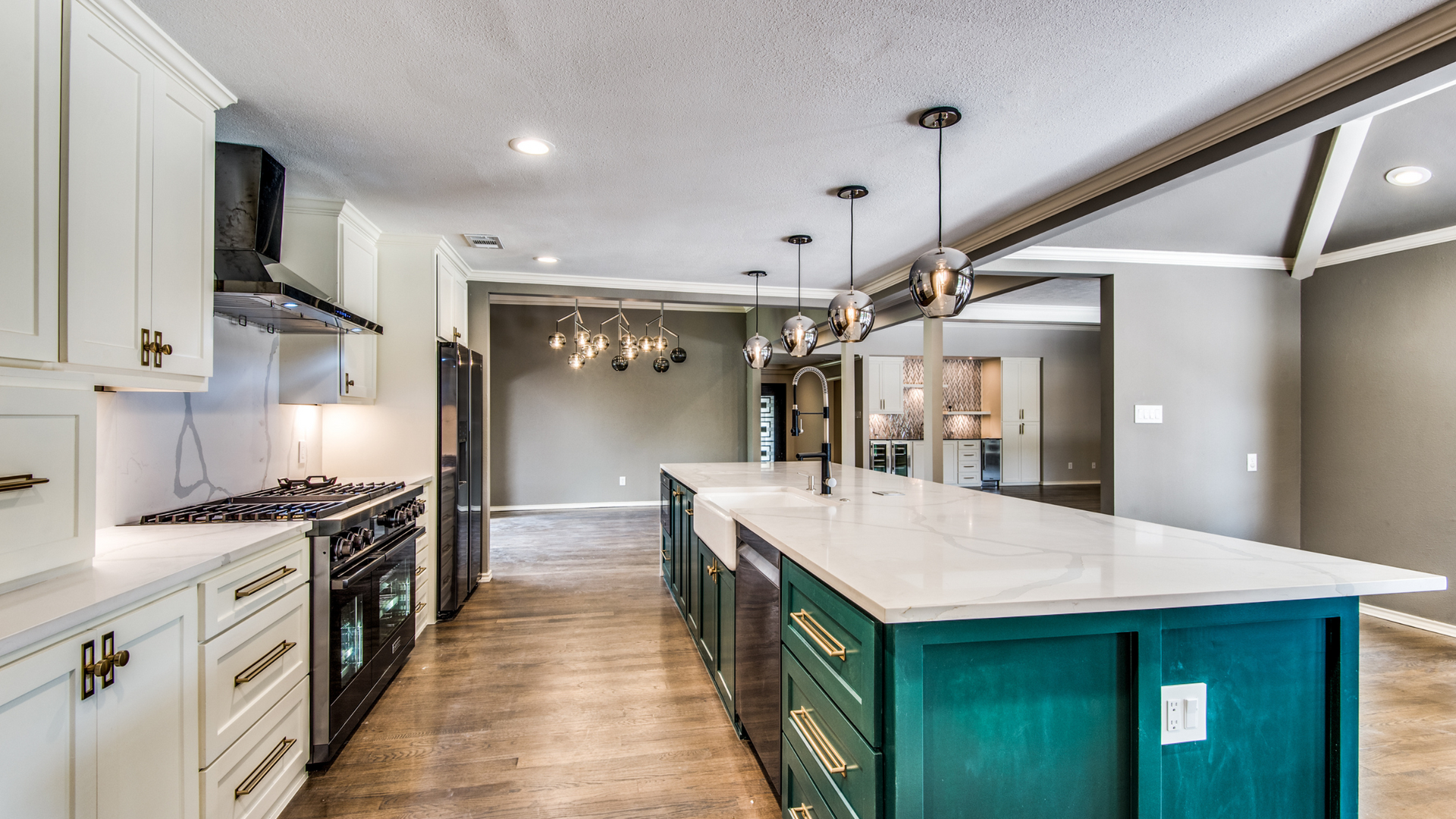 Modern kitchen with a teal island, white cabinets, and wood floors.