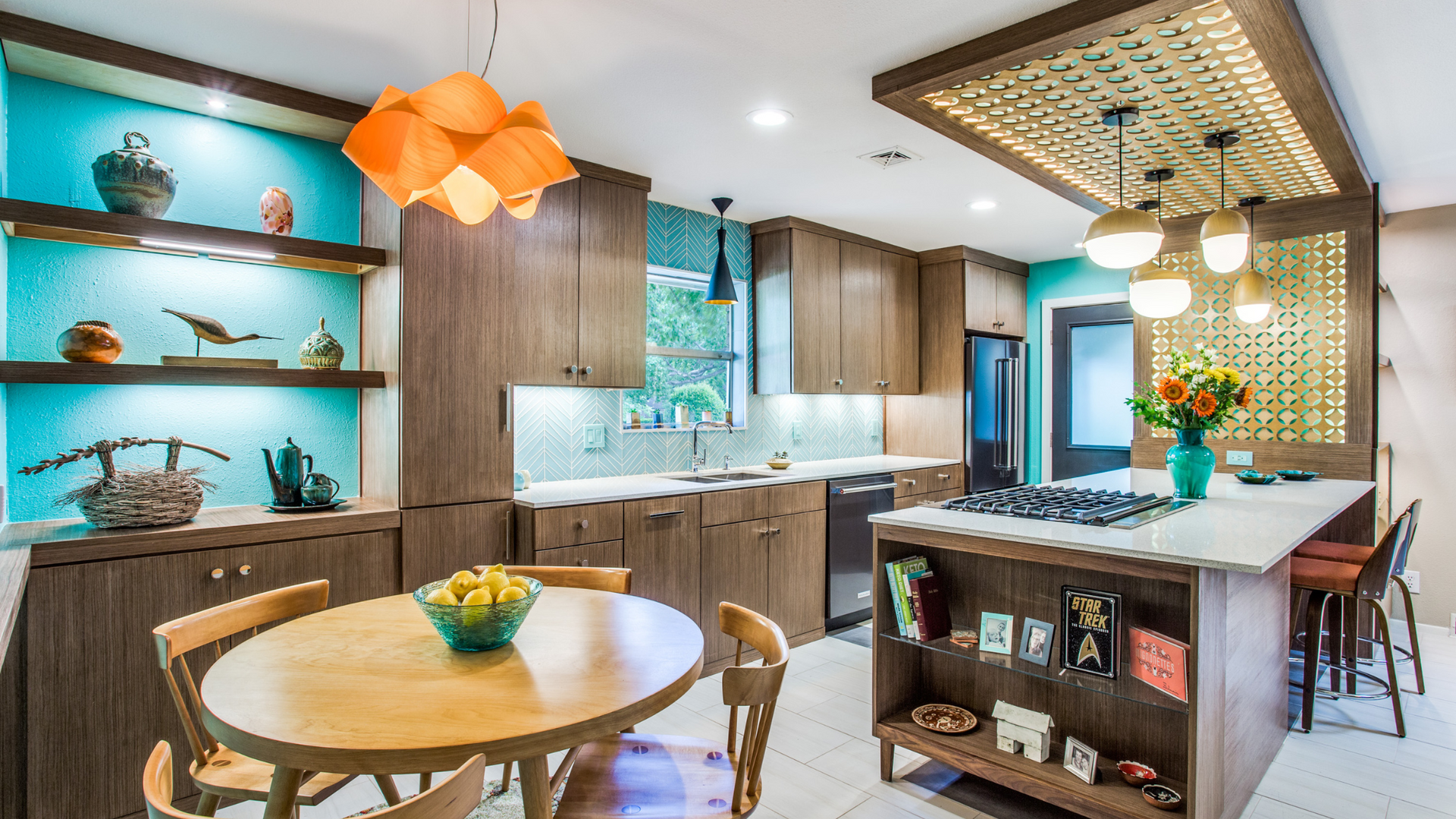Modern kitchen with teal accents, wood cabinets, island, and dining area.