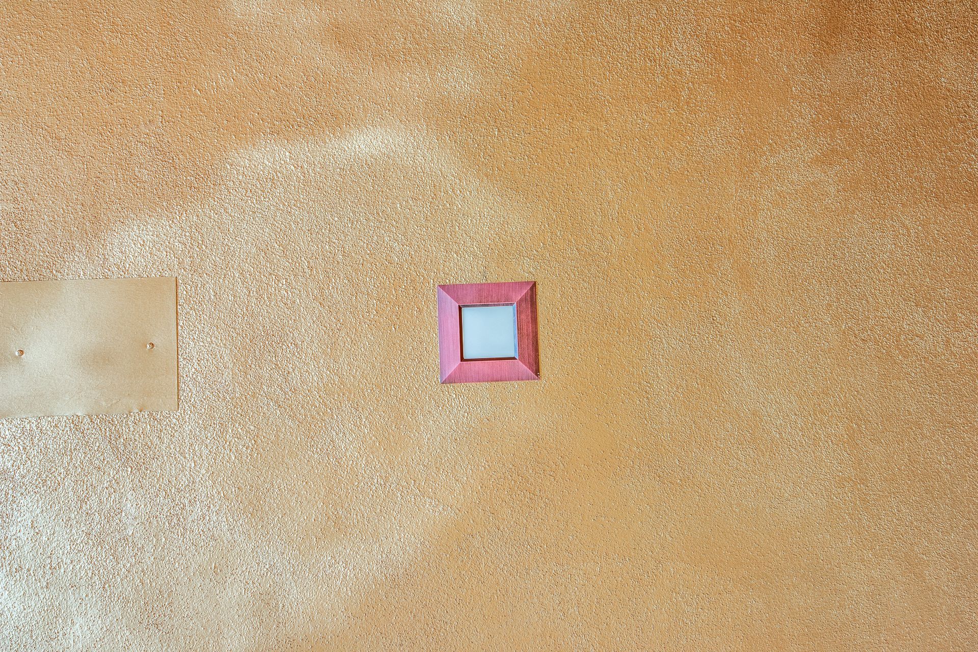 A picture frame is hanging on a cork board on a wall.