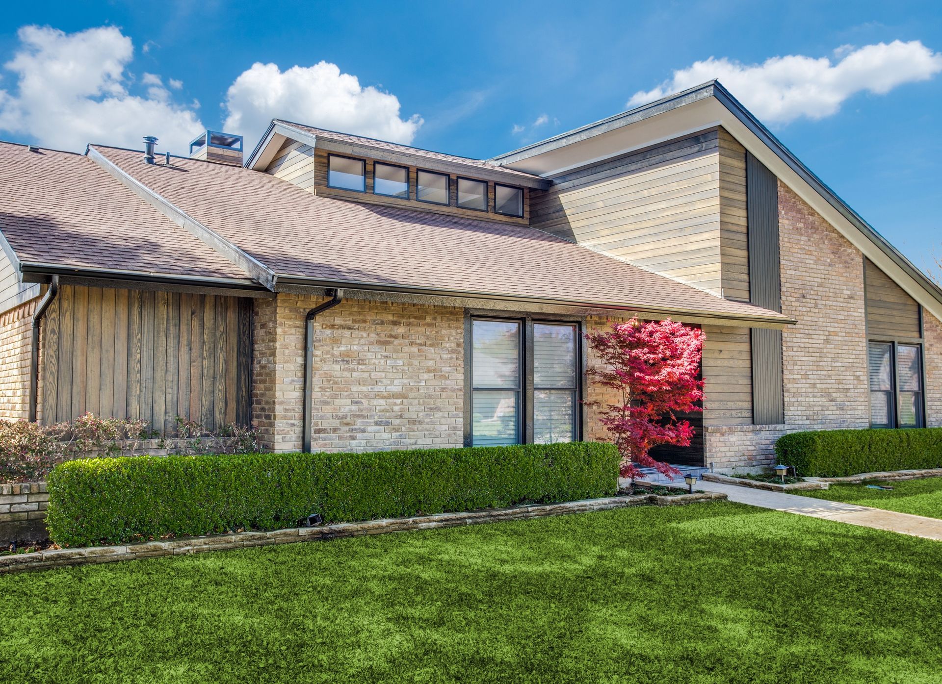 A large brick house with a lush green lawn in front of it.
