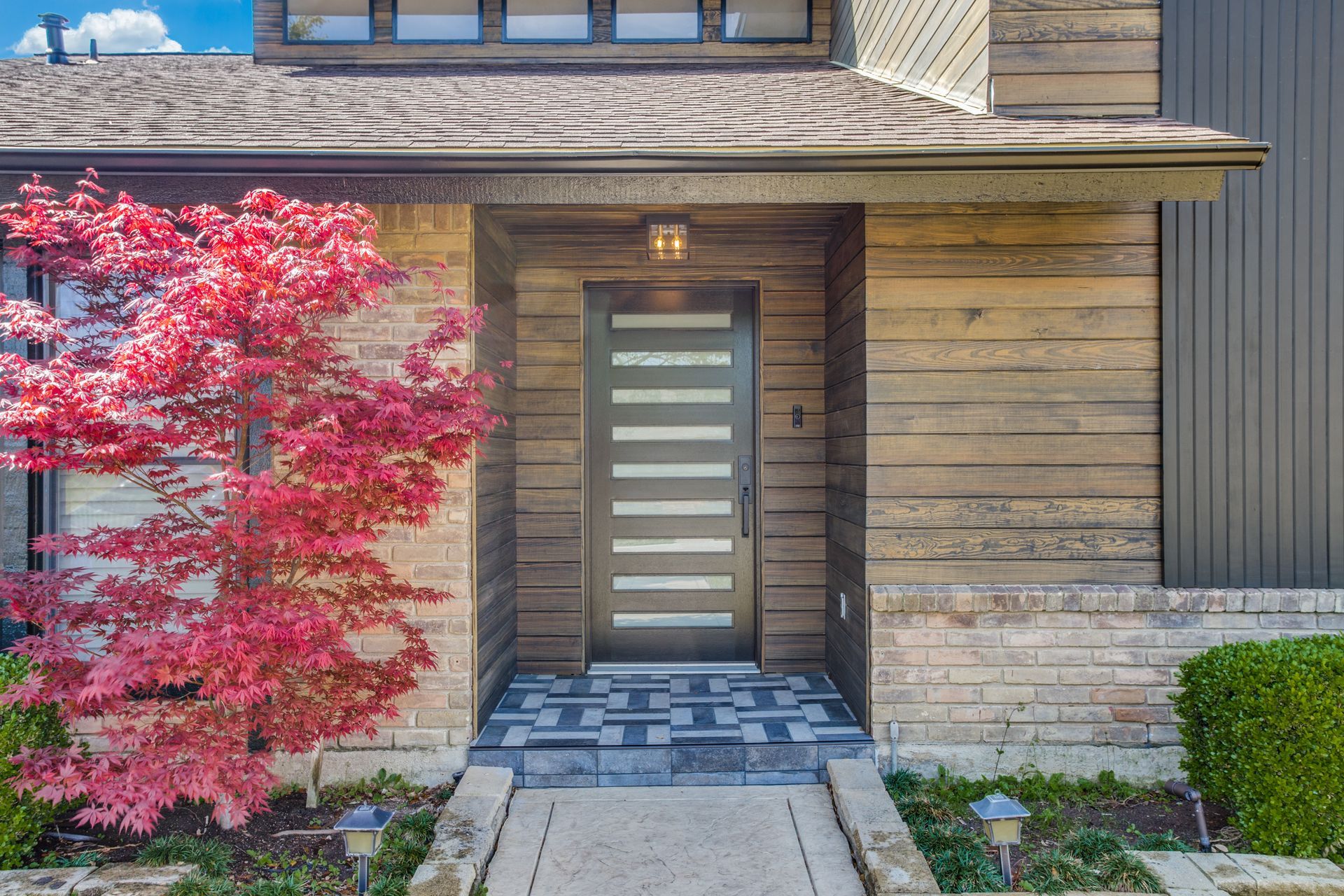 The front door of a house remodel with a tree in front of it.