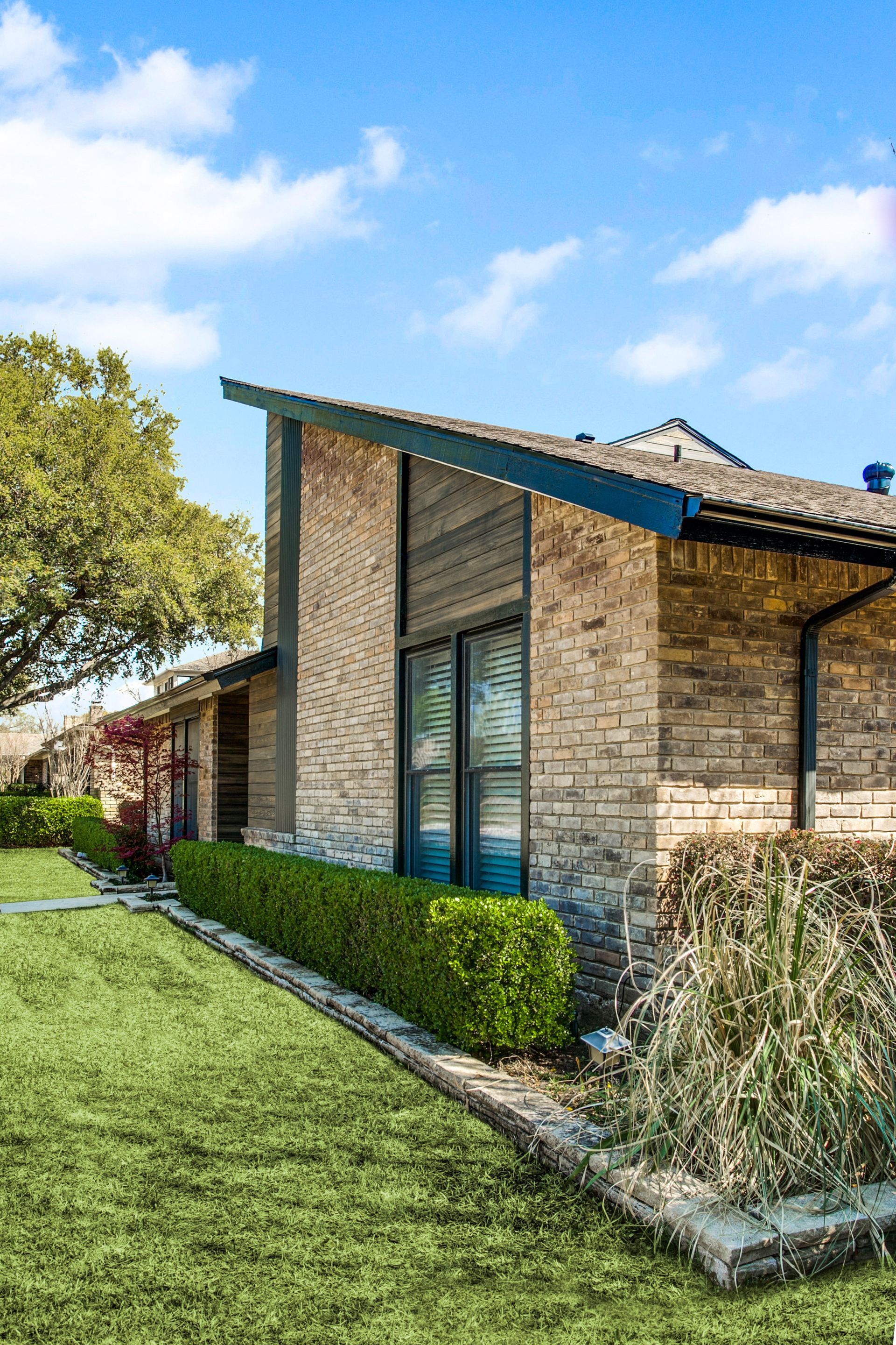 A brick house remodel with a lush green lawn in front of it.