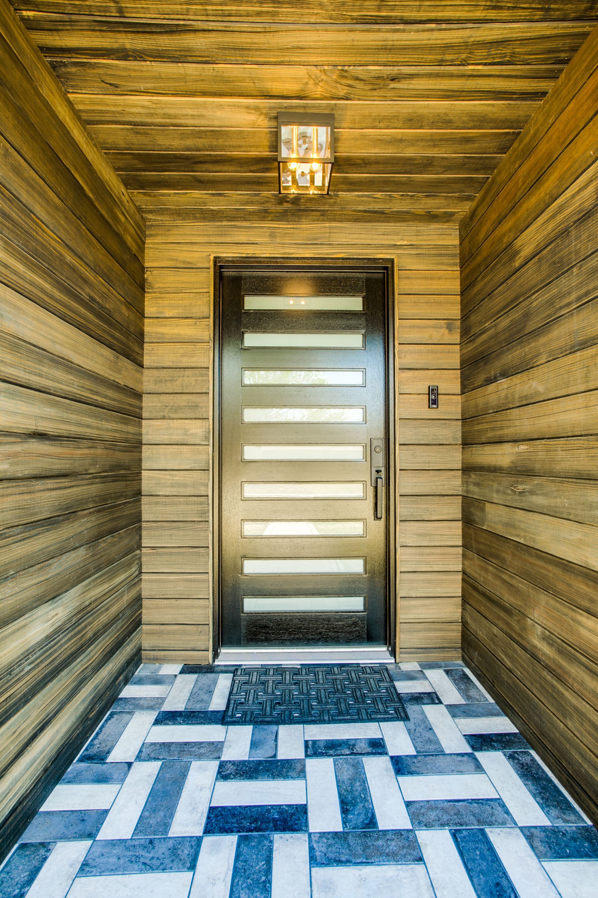 A doorway with a rug on the floor and a wooden wall.