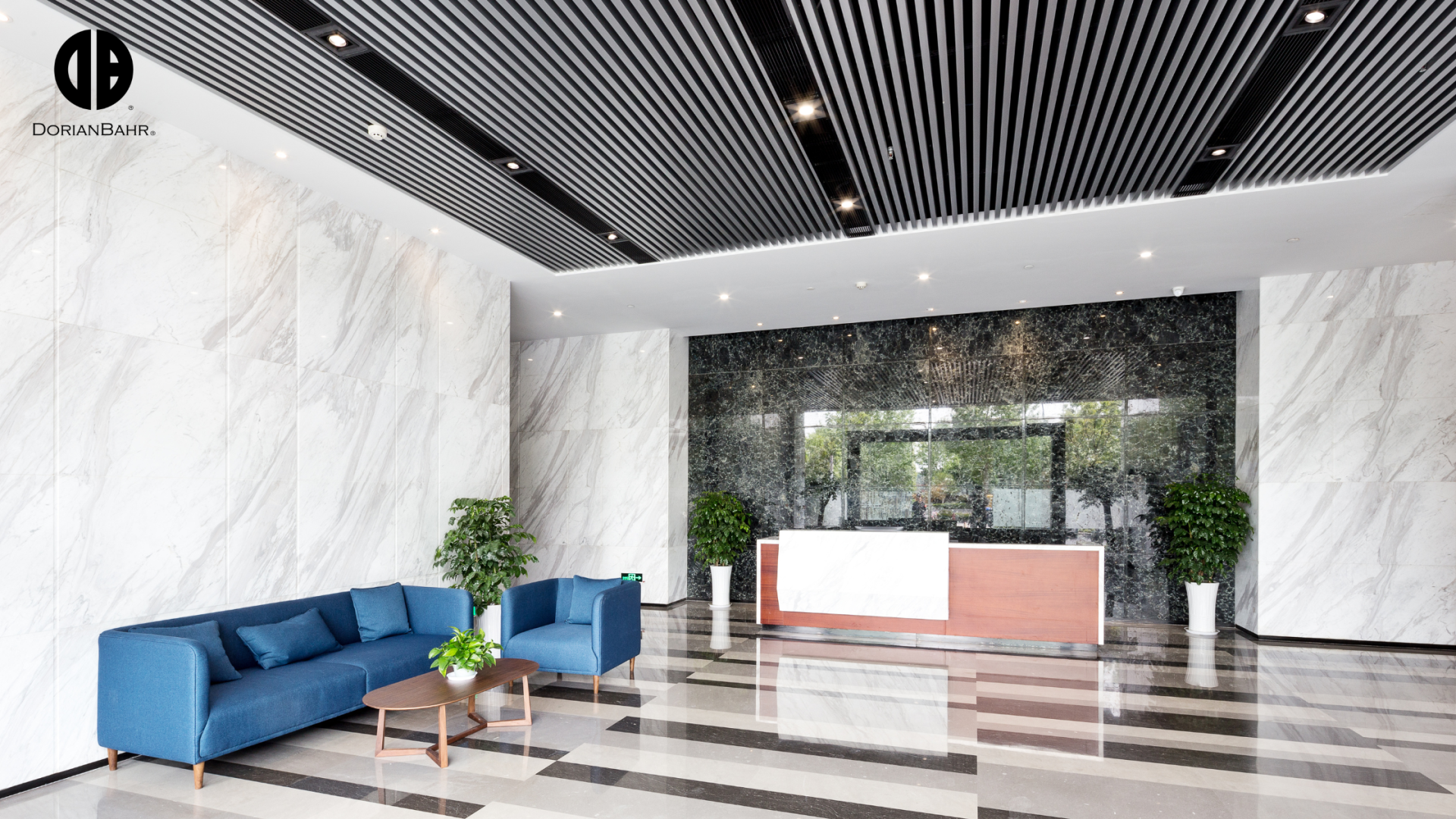 A lobby with a couch , chairs , and a reception desk.