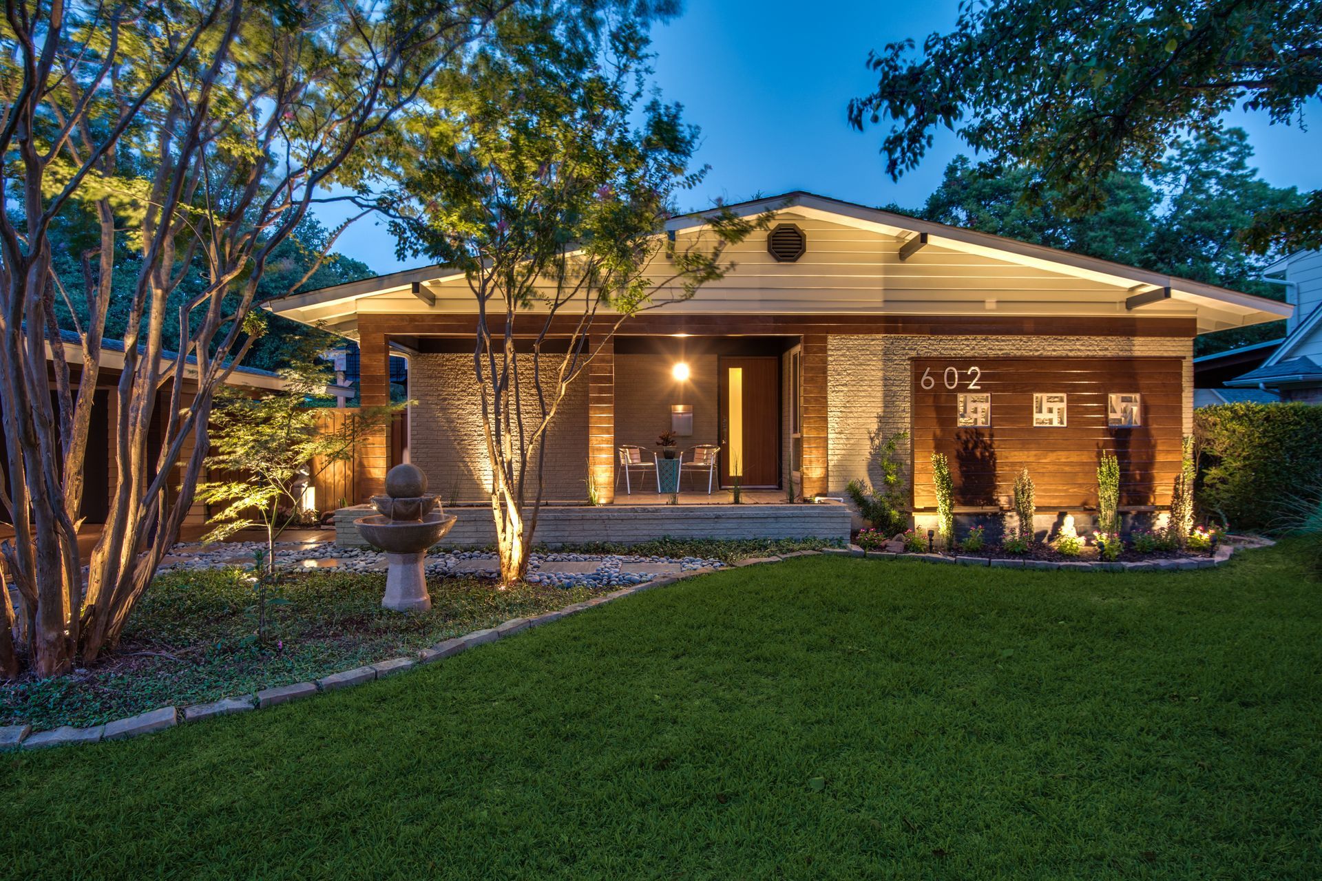 A house remodel with a large lawn in front of it is lit up at night.
