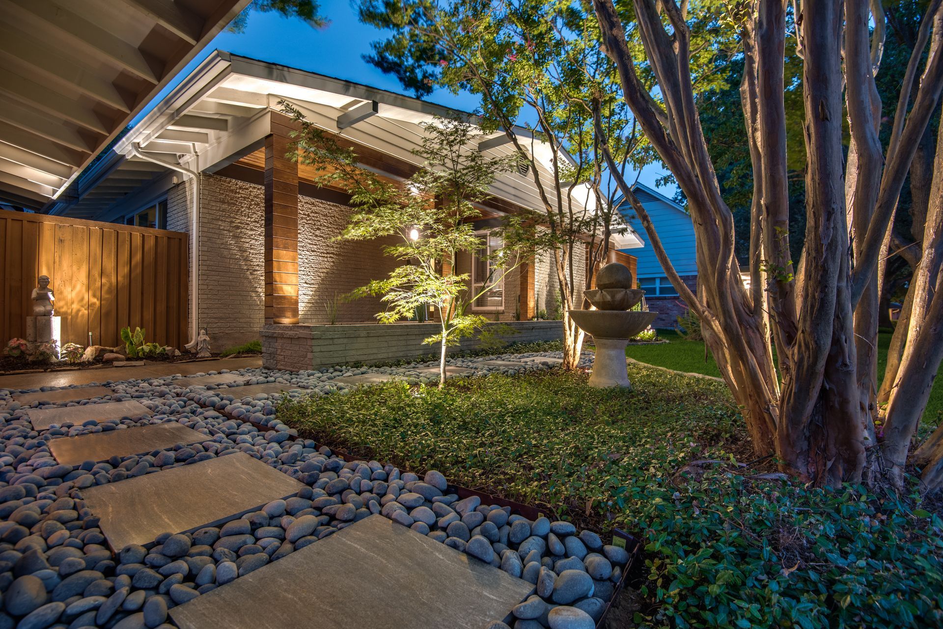 A house remodel with a stone walkway leading to it is lit up at night.