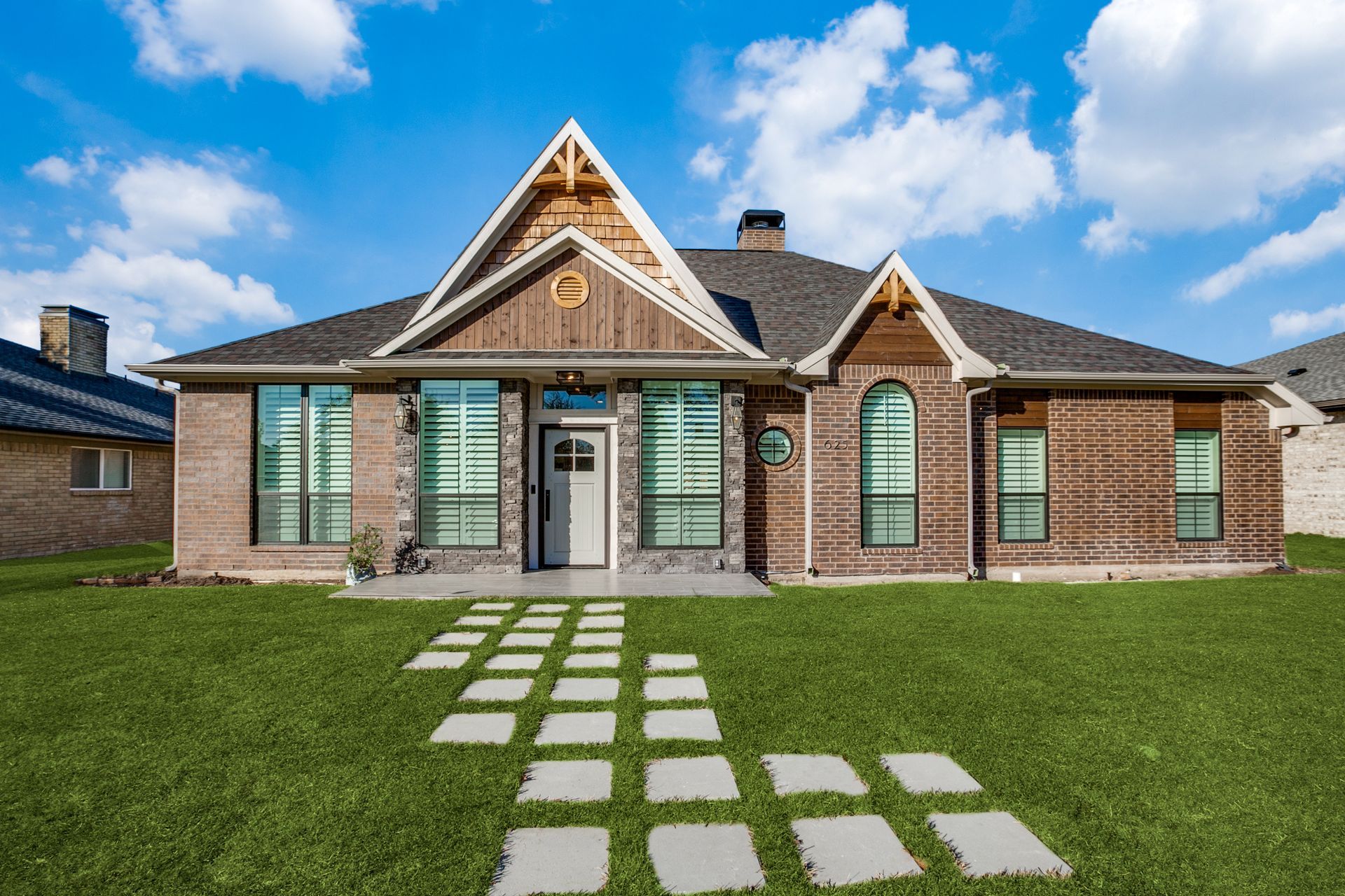 A large brick house remodel with a walkway leading to it