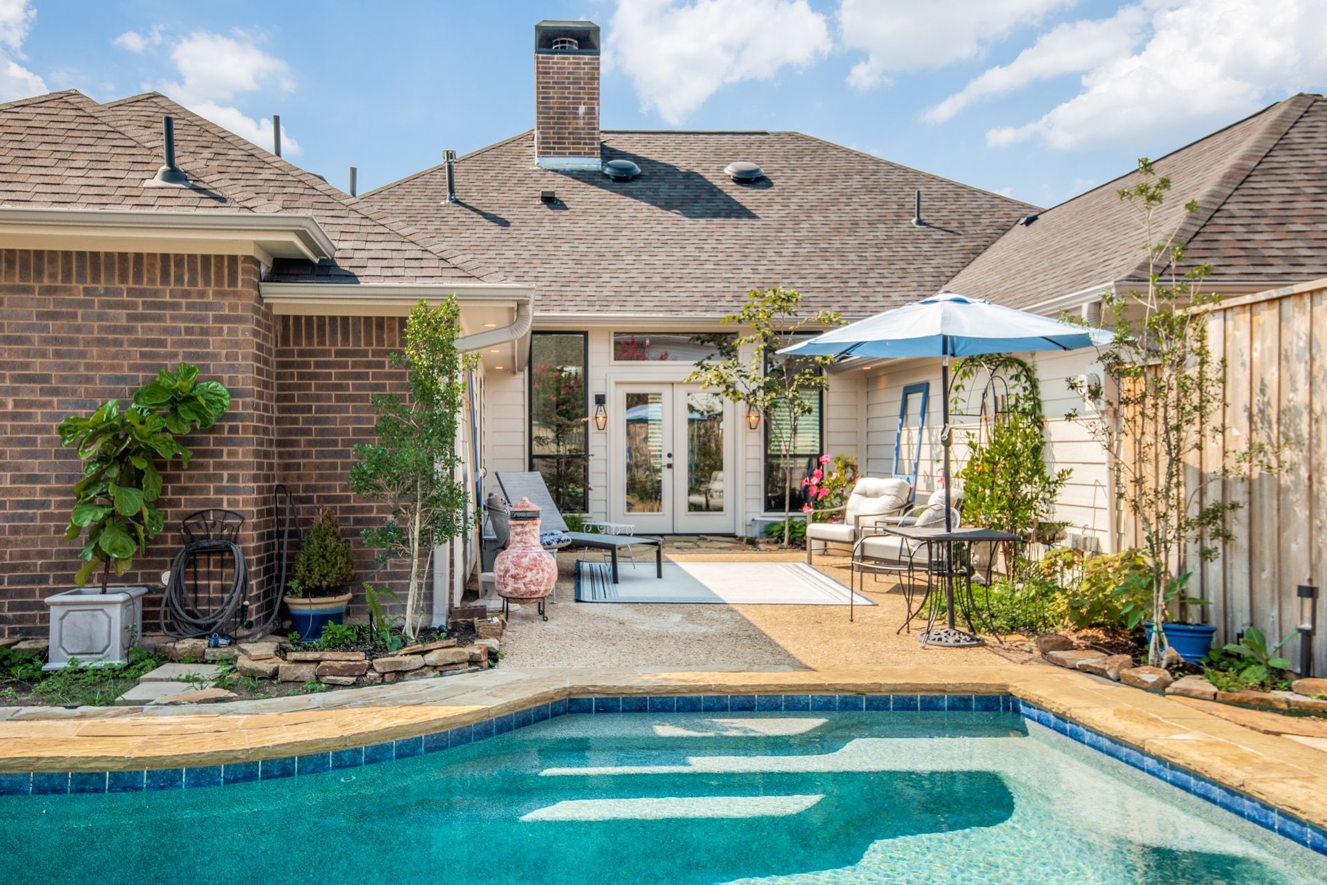 There is a large swimming pool in the backyard of a house remodel.