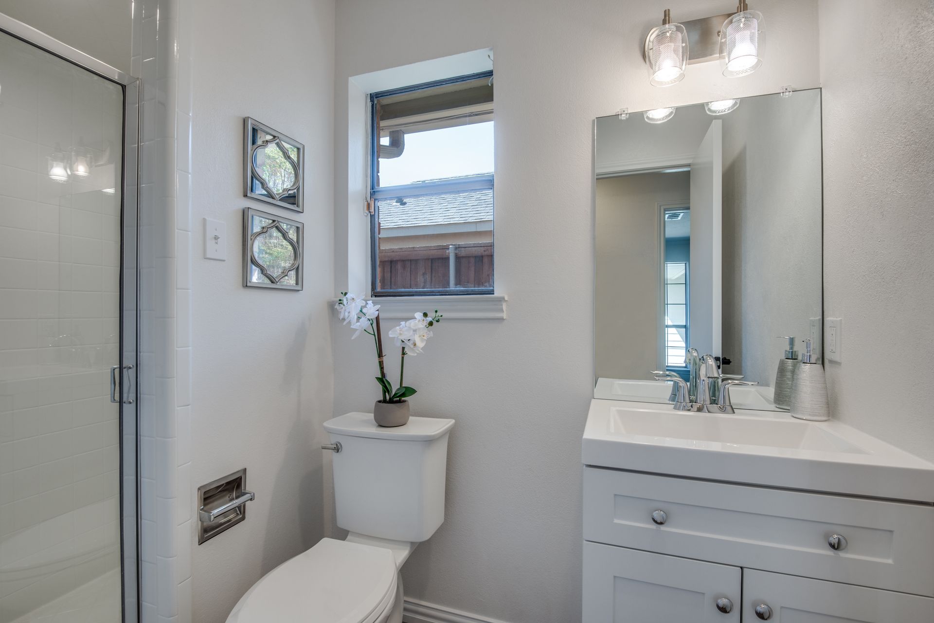 A bathroom remodel with a toilet , sink , mirror and shower.