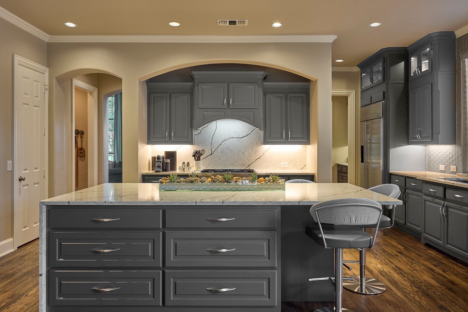 A kitchen with gray cabinets and a large island in the middle.