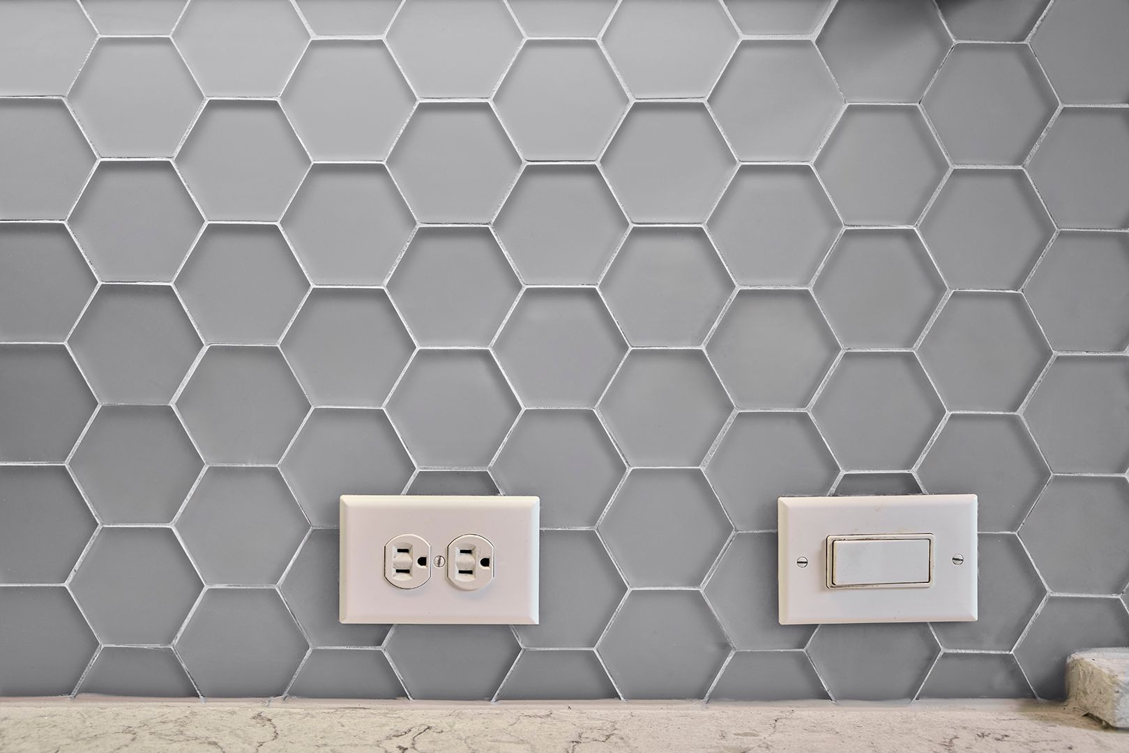 There are two electrical outlets and a light switch on the wall.