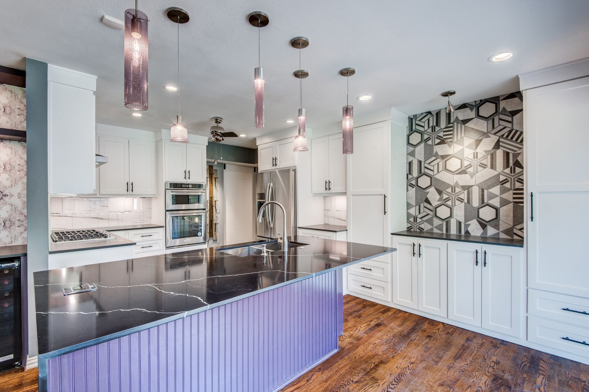 A kitchen with white cabinets , black counter tops , and a purple island.