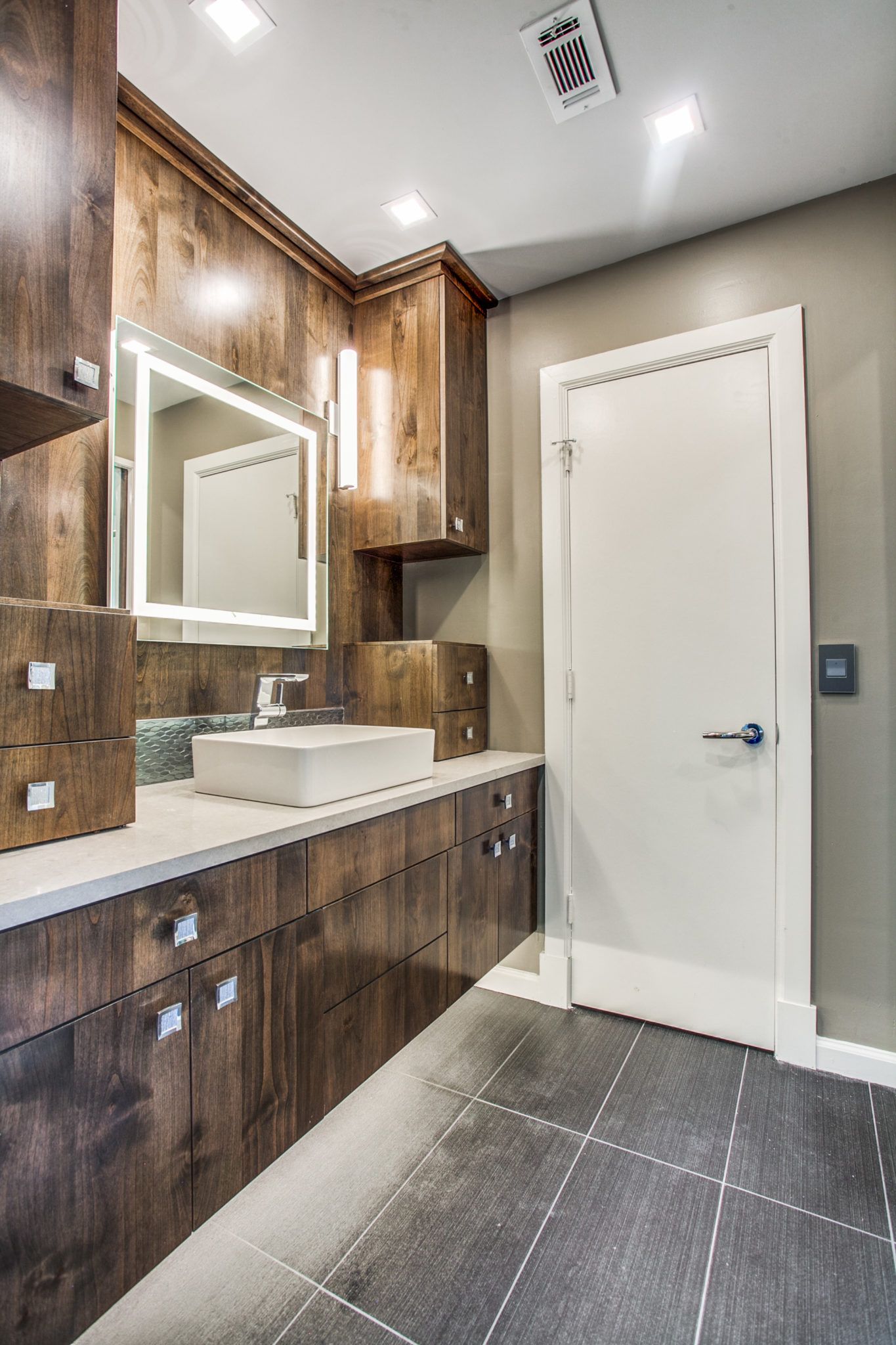A bathroom with a sink , mirror and cabinets.