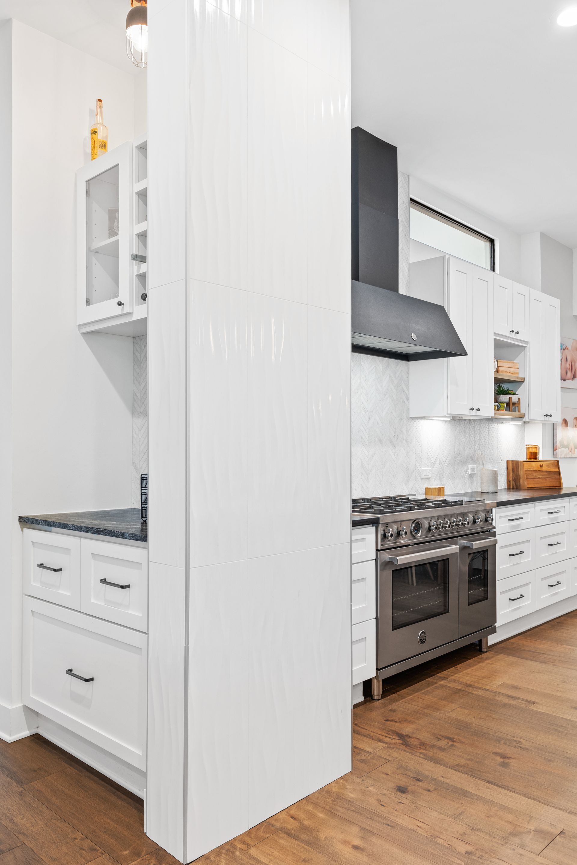 A kitchen with white cabinets , stainless steel appliances , and hardwood floors.