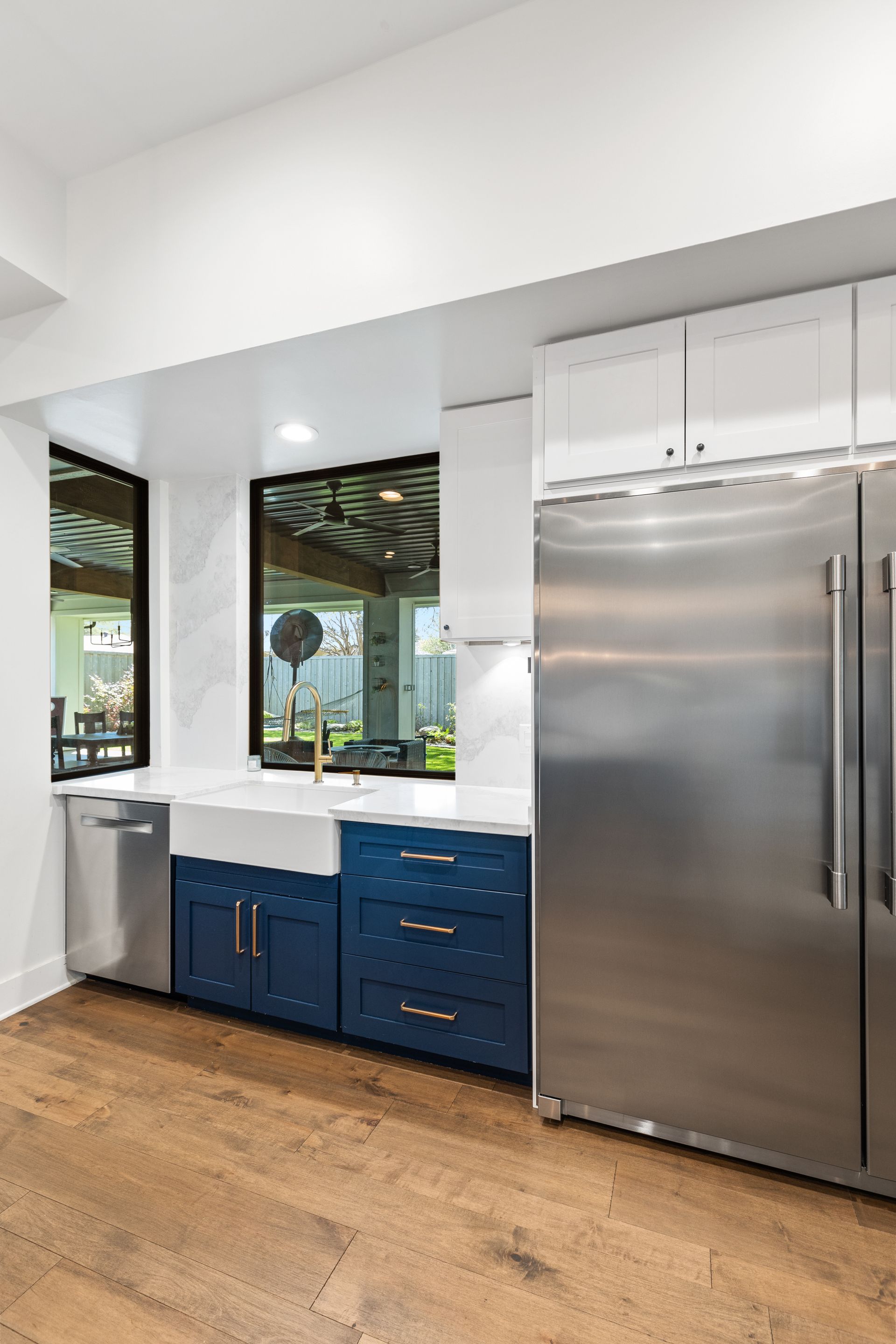 A kitchen with stainless steel appliances , blue cabinets , a sink and a refrigerator.