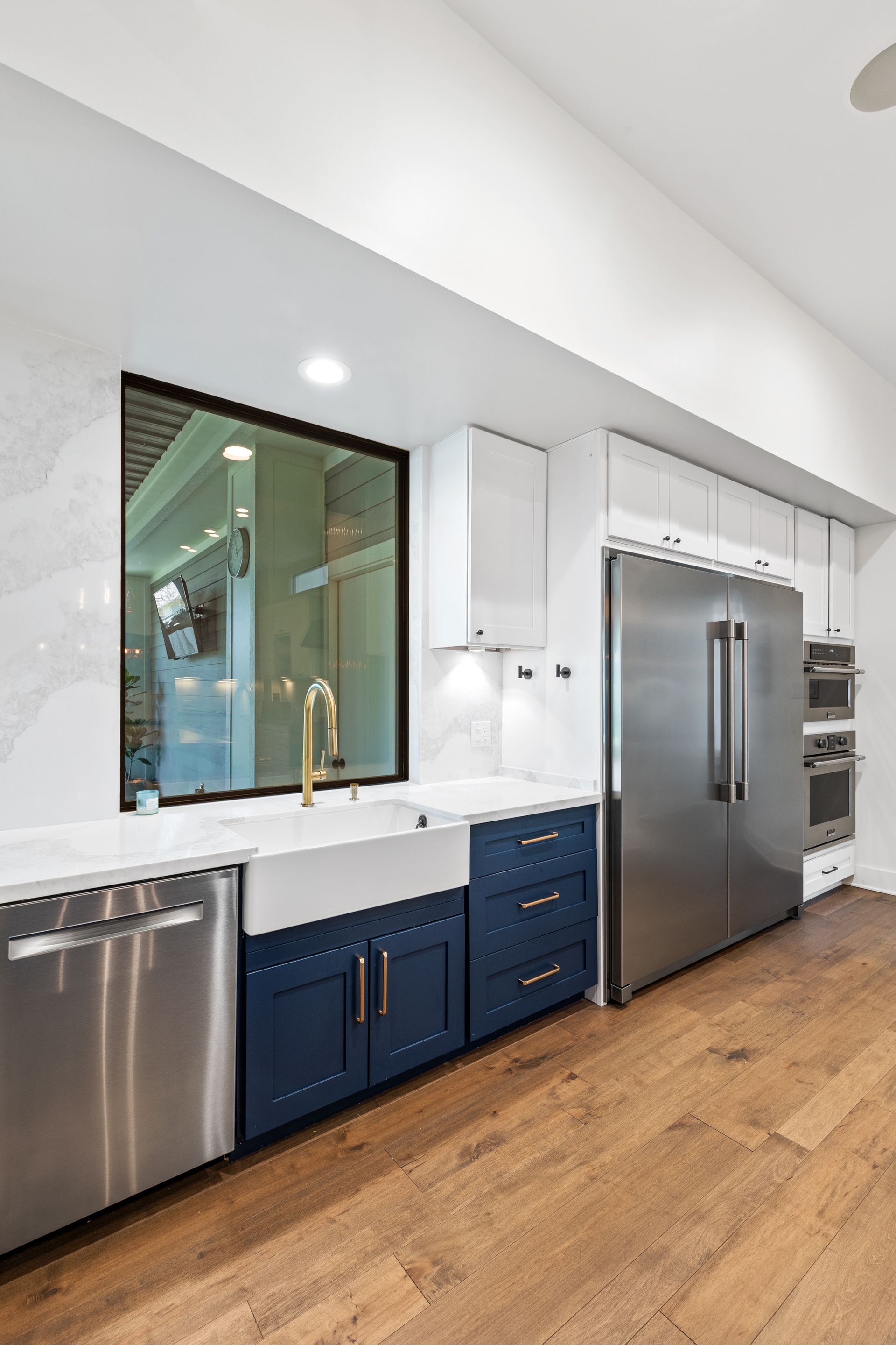 A kitchen with blue cabinets , stainless steel appliances , a sink and a refrigerator.