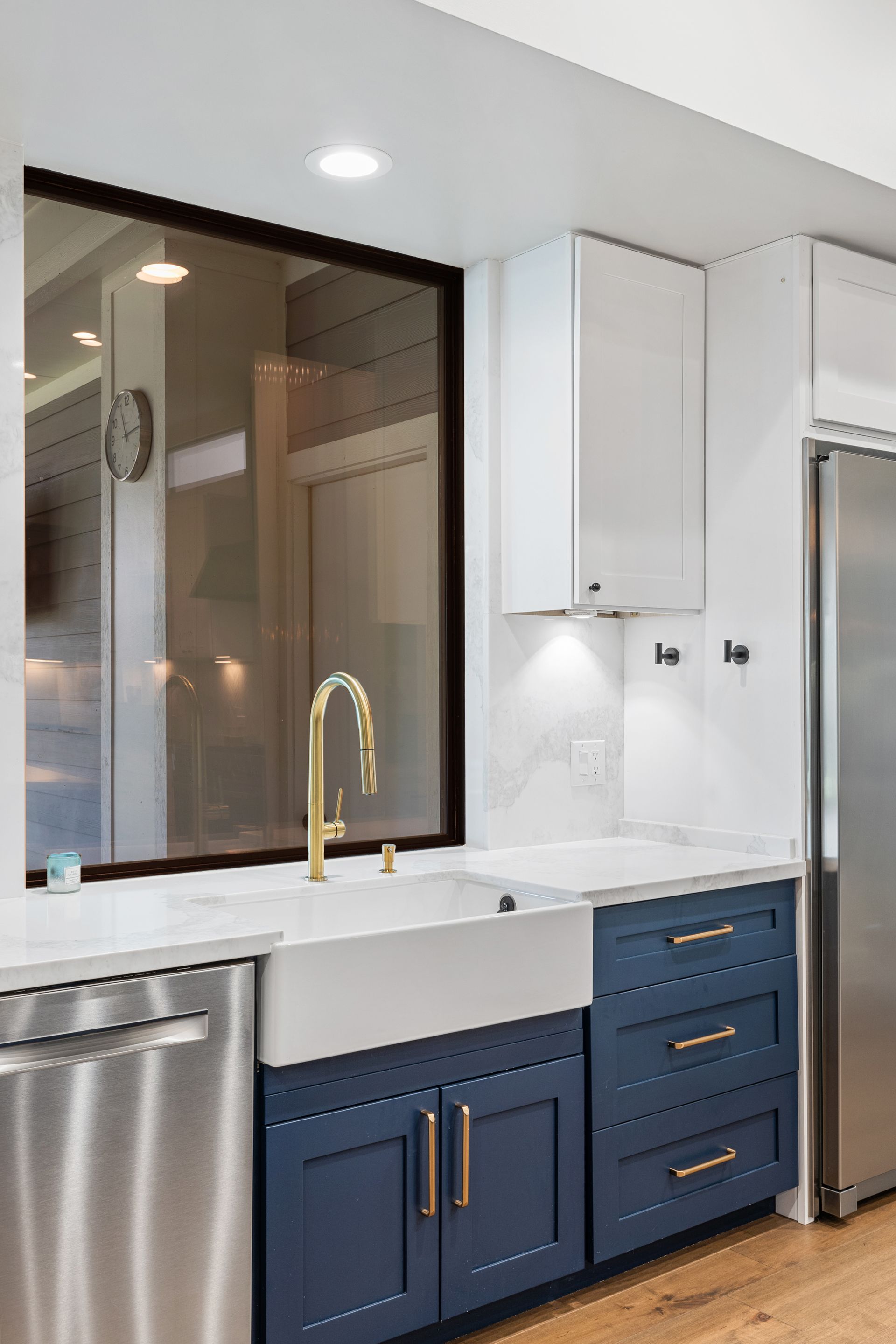 A kitchen with blue cabinets , stainless steel appliances , a sink , and a large window.