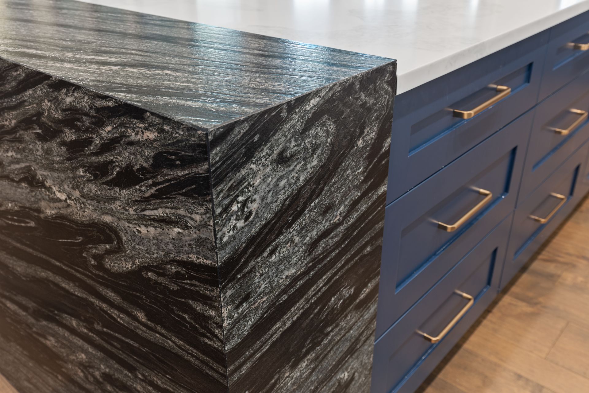 A kitchen with a black granite counter top and blue cabinets.