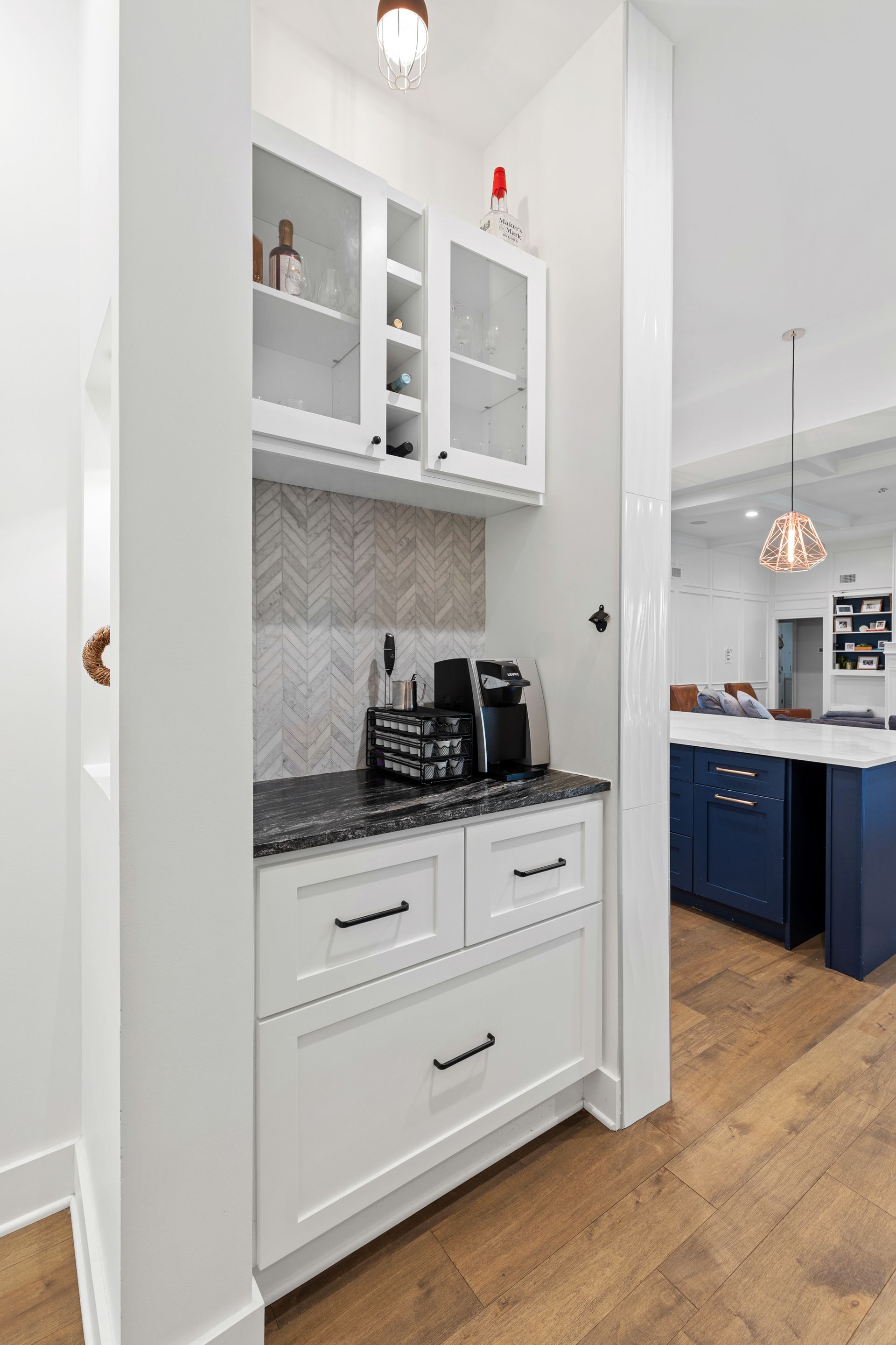 A kitchen with white cabinets and blue cabinets and a coffee maker.