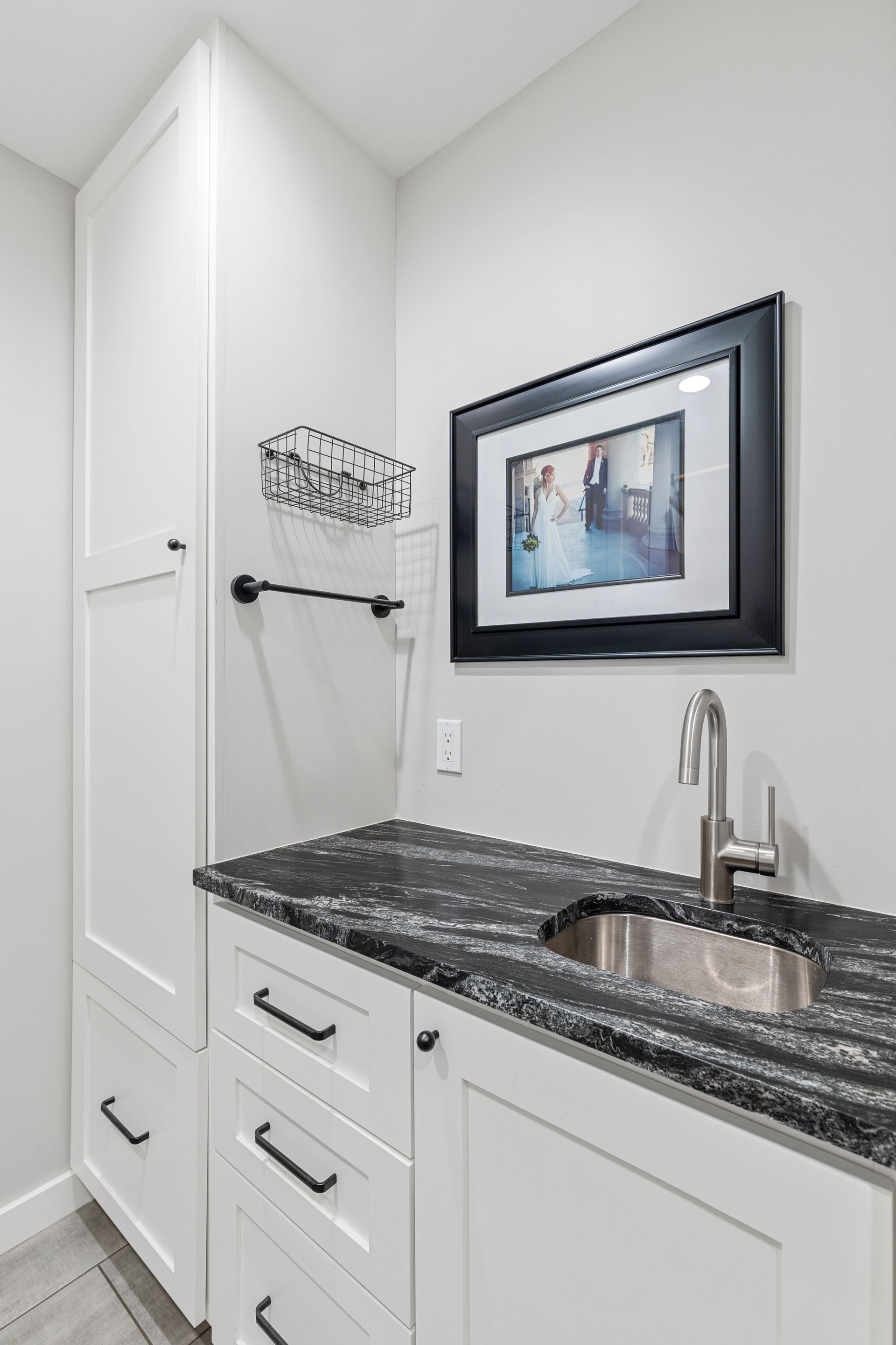 There is a picture on the wall above the sink in the laundry room.