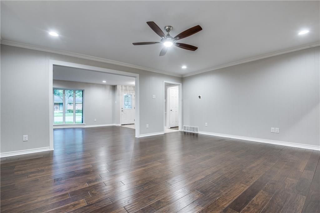 An empty living room with hardwood floors and a ceiling fan.