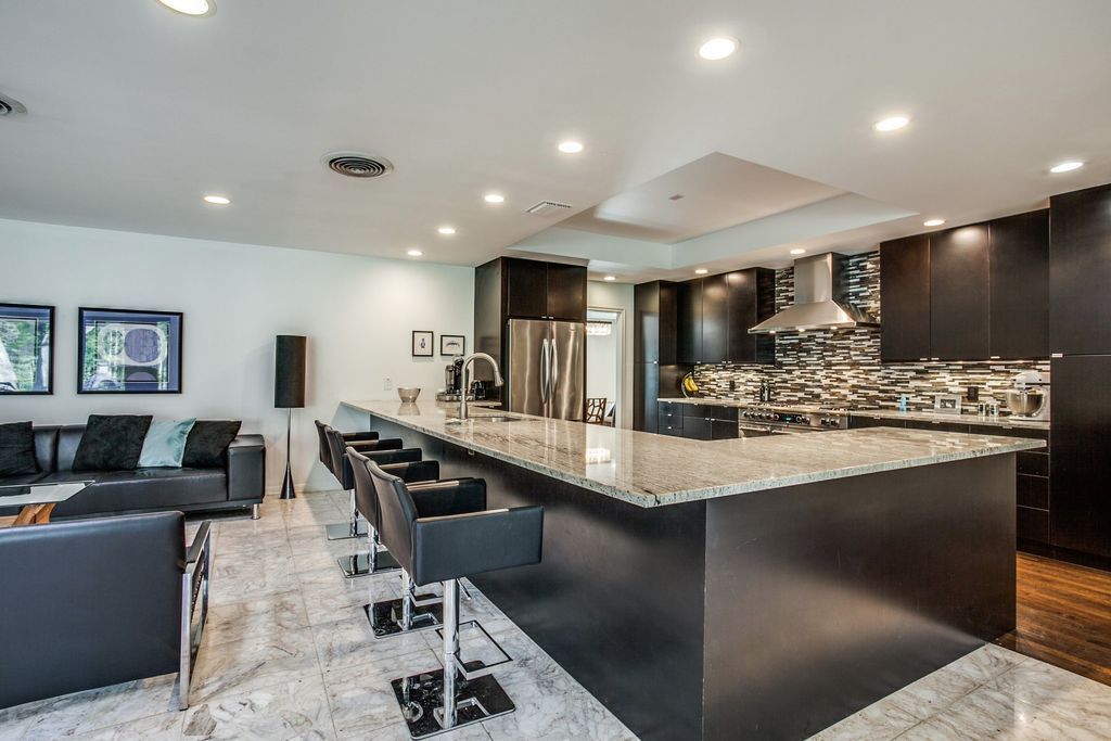 A large kitchen with a large island and a living room.