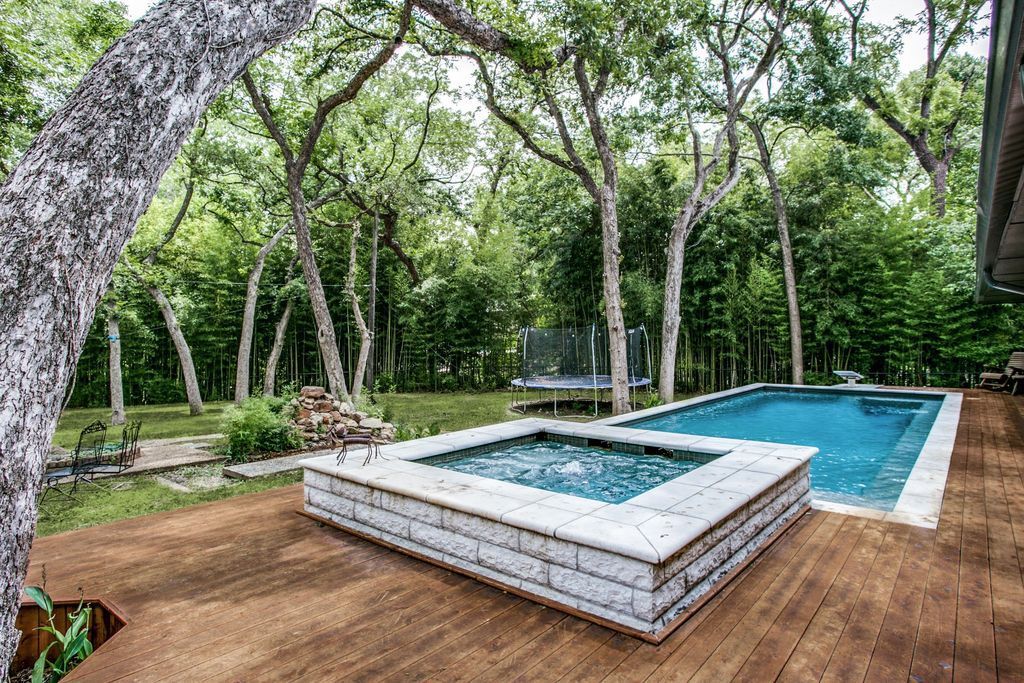 A large swimming pool surrounded by trees and a wooden deck.