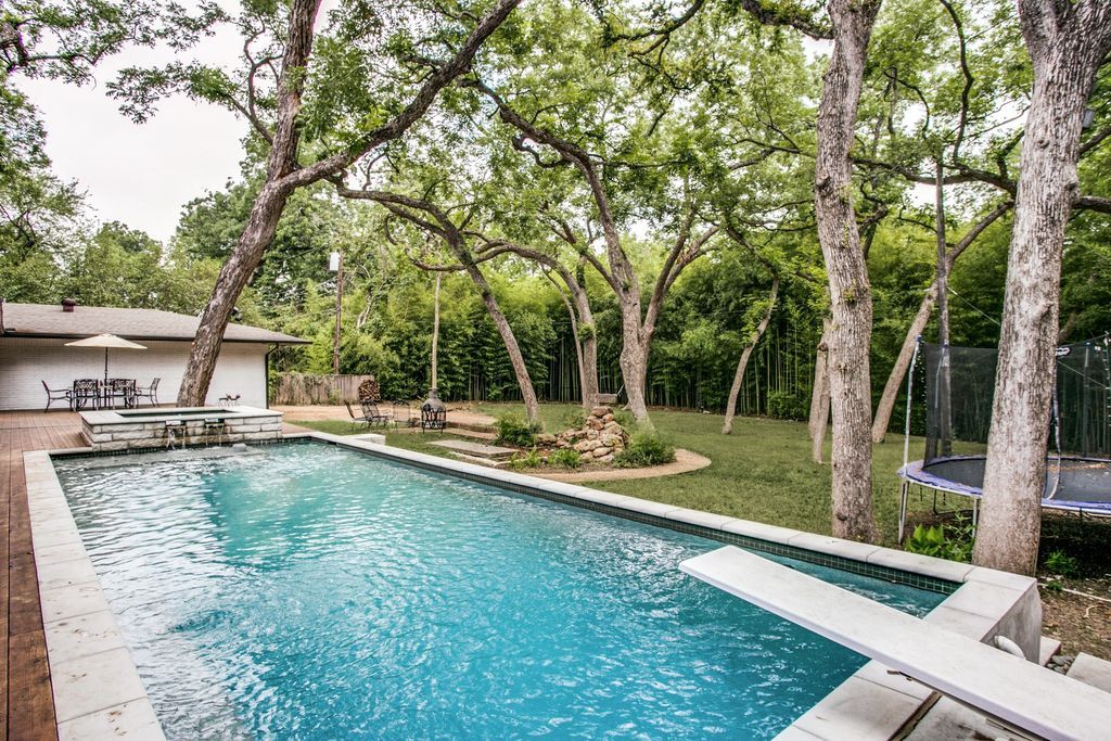 A large swimming pool surrounded by trees in a backyard.