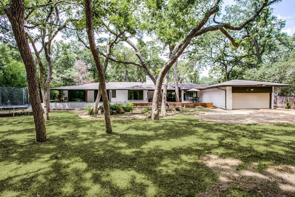 A house with a large lawn and trees in front of it.