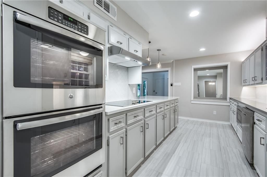 A kitchen with stainless steel appliances and white cabinets.