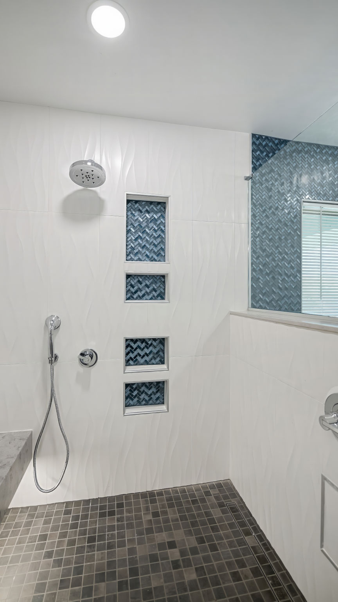 Modern bathroom with a tiled shower and mosaic accent in shades of blue and gray.
