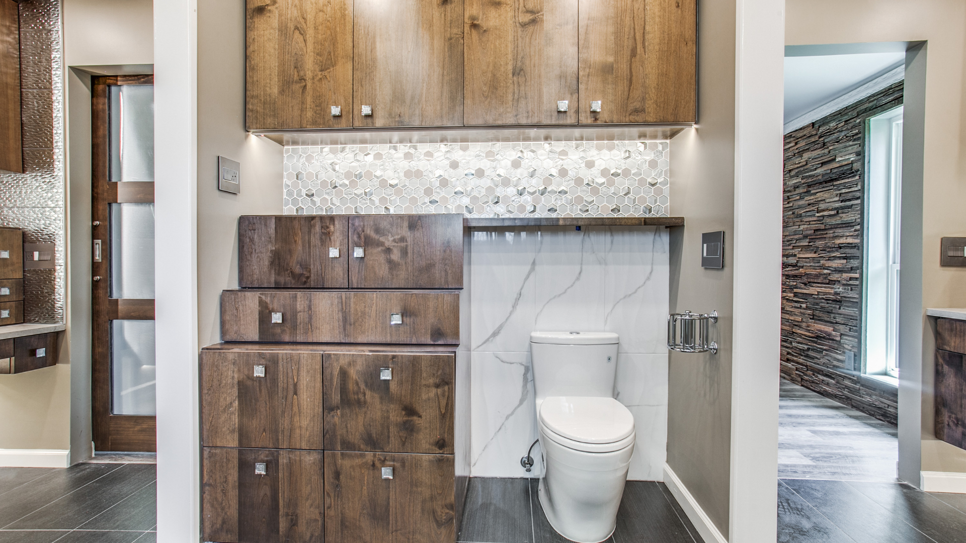 A modern bathroom with wood cabinets, a toilet, and mosaic and white tile accents.