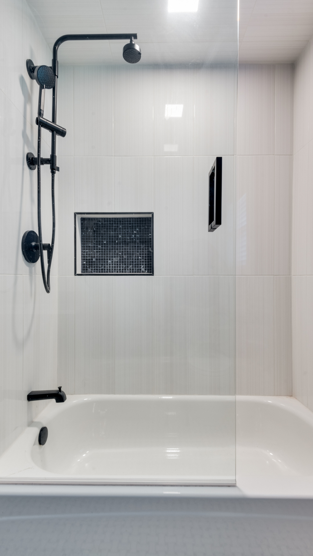 White bathroom with a black shower fixture and a glass shower door.