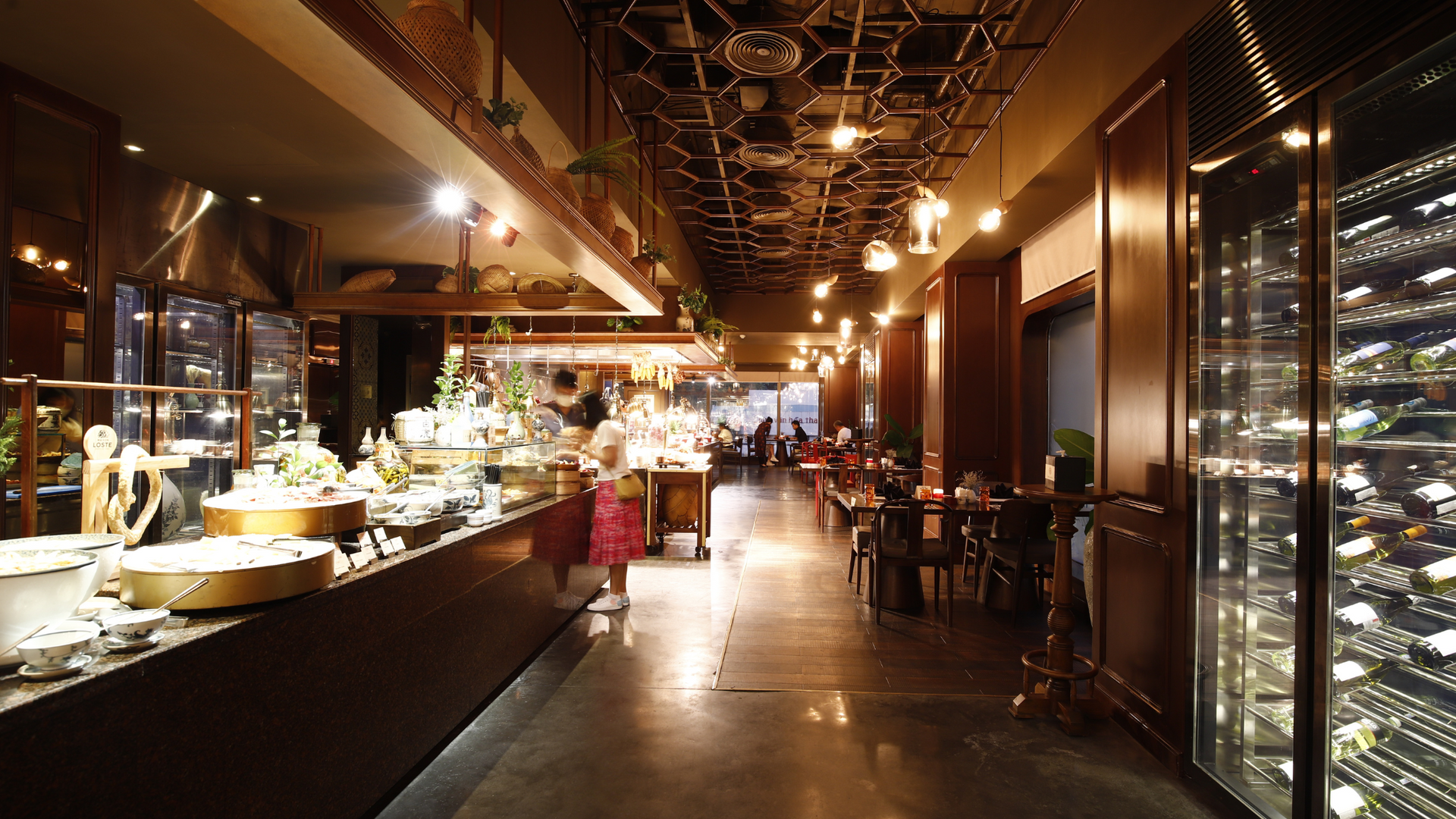 Inside a restaurant with glass display cases, warm lighting, and dark wood accents. A child examines a display.