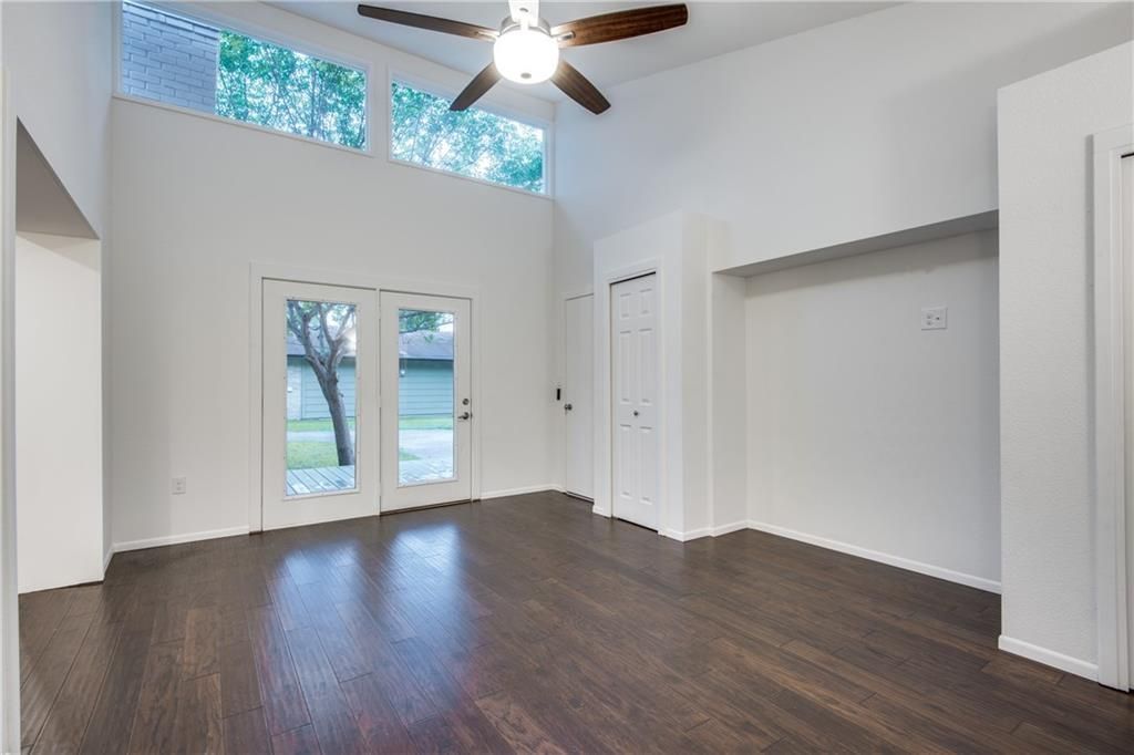 An empty living room with hardwood floors and a ceiling fan.