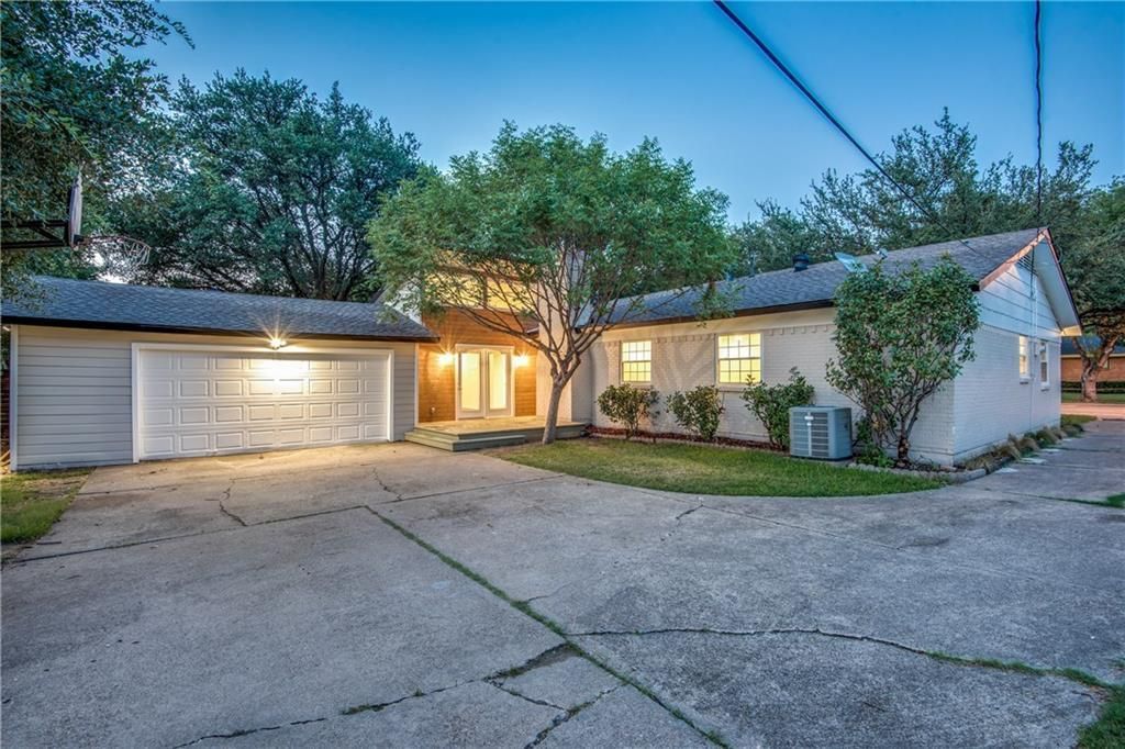 A white house remodel with two garages and a driveway is for sale.